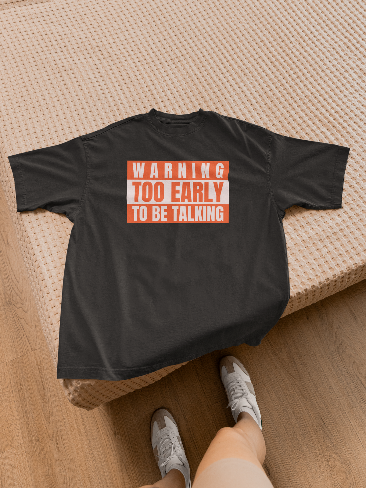 'Warning Too Early To Be Talking' t-shirt in black, laid on bed with sneaker, funny sarcastic gift idea