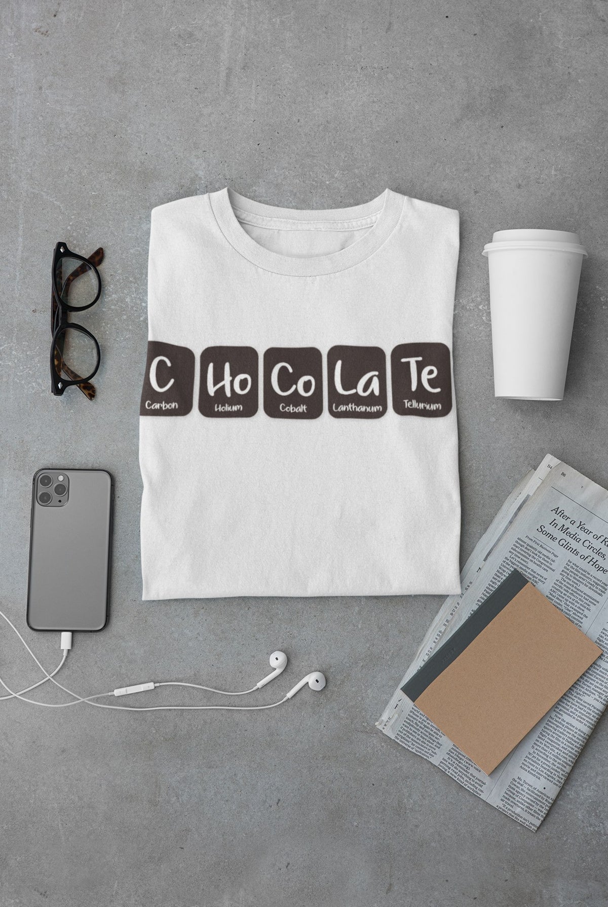 C-Ho-Co-La-Te tee in white, flat lay on concrete with glasses, phone and coffee, science gift