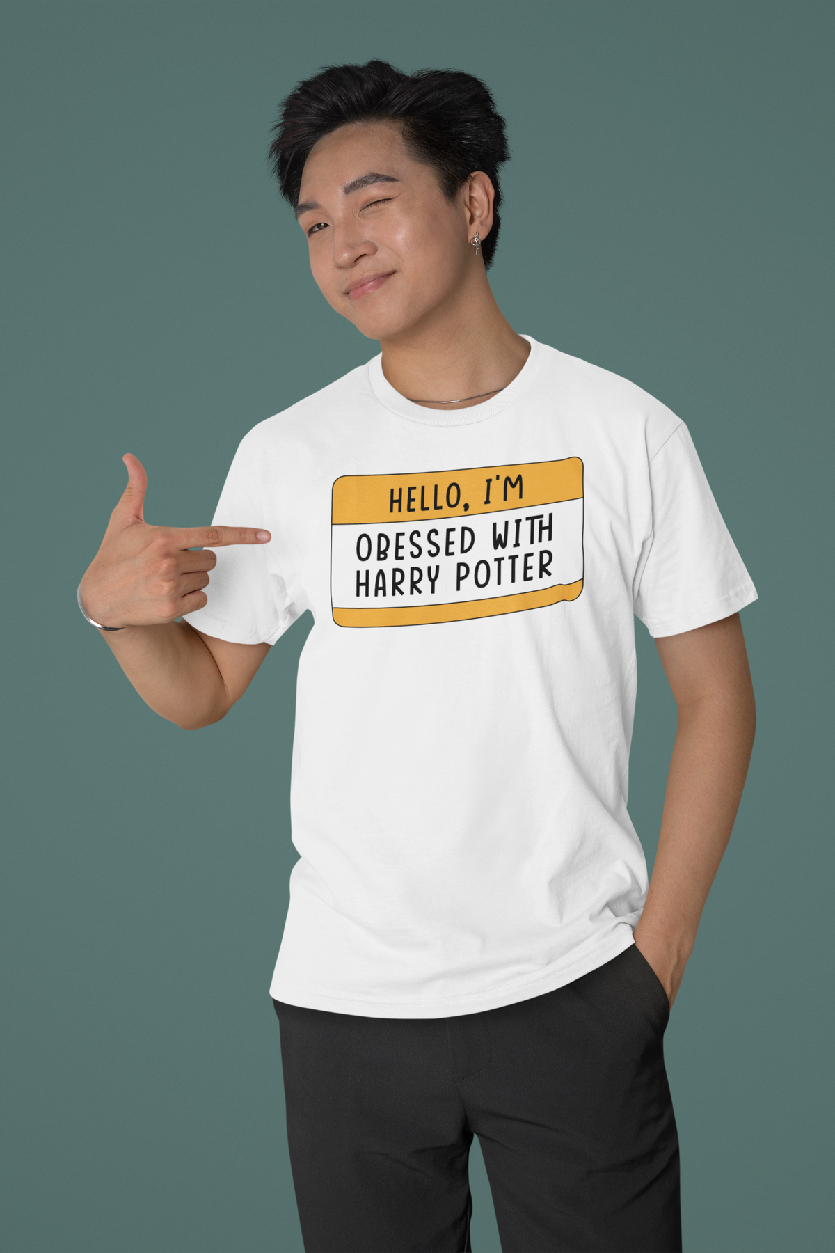 Hello I'm Obsessed With Harry Potter name tag T-shirt in white, man pointing at design, teal backdrop, tee