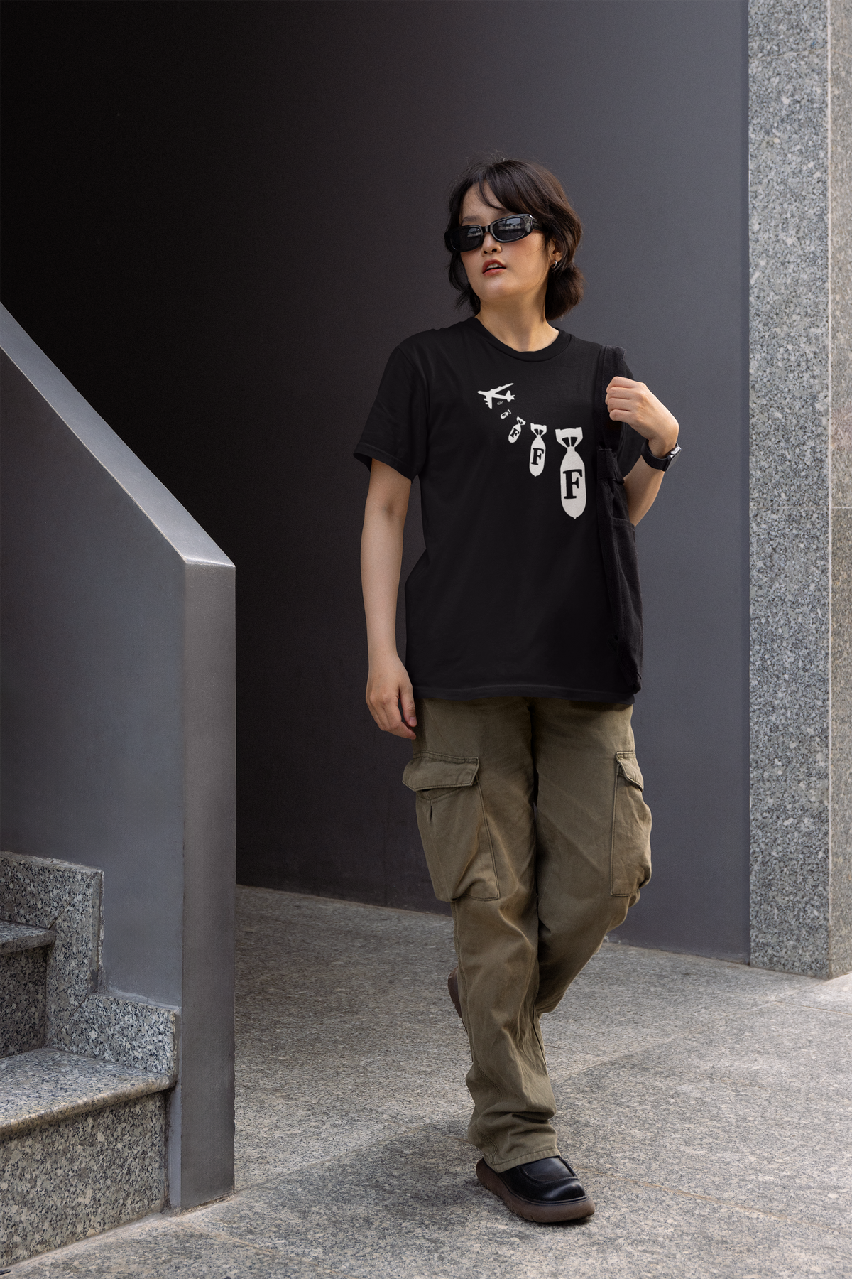 "F Bomb" tee in black, person wearing it on outdoor stairs, funny sarcastic gift t-shirt