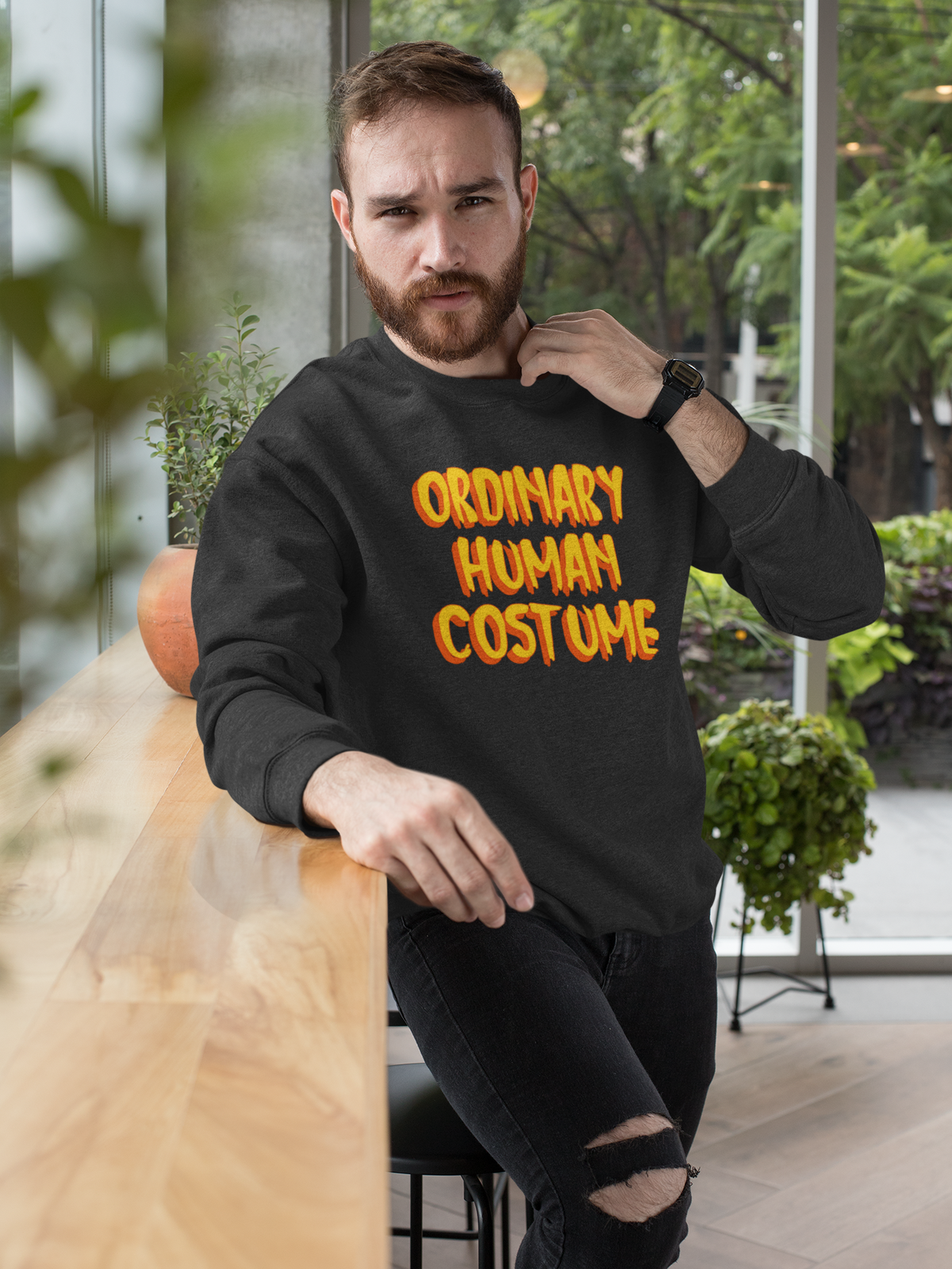 'Ordinary Human Costume' funny halloween sweatshirt in black, bearded man sitting outdoors, funny gift