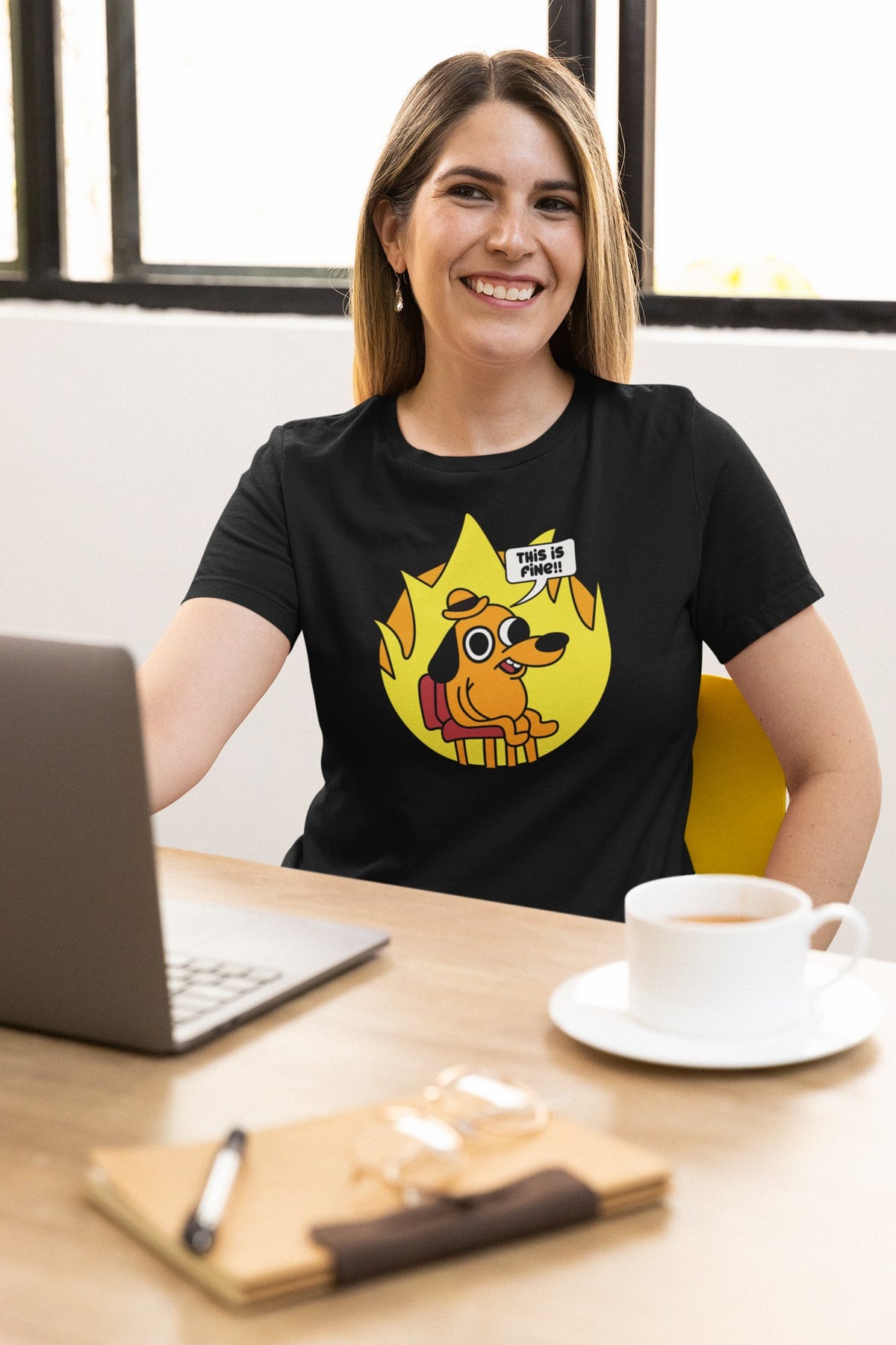 This Is Fine tee in black, woman at a cafe table with a laptop, funny meme gift shirt