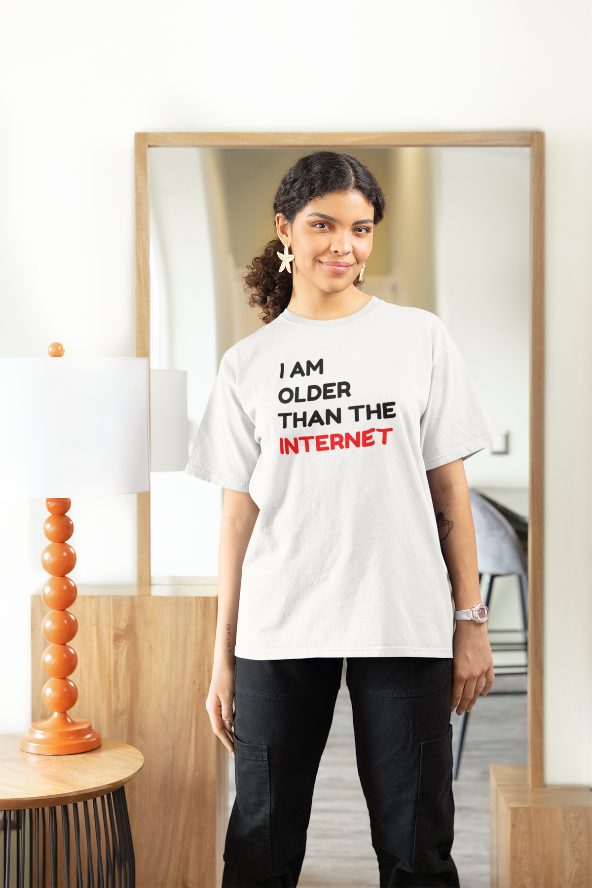 'I Am Older Than the Internet' t-shirt in white, woman wearing it in a stylish room, funny nostalgic pun gift