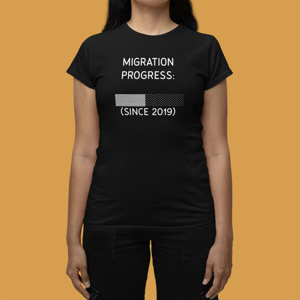 'Migration Progress: (Since 2019)' women's tee in black, close-up on woman against orange backdrop, funny gift