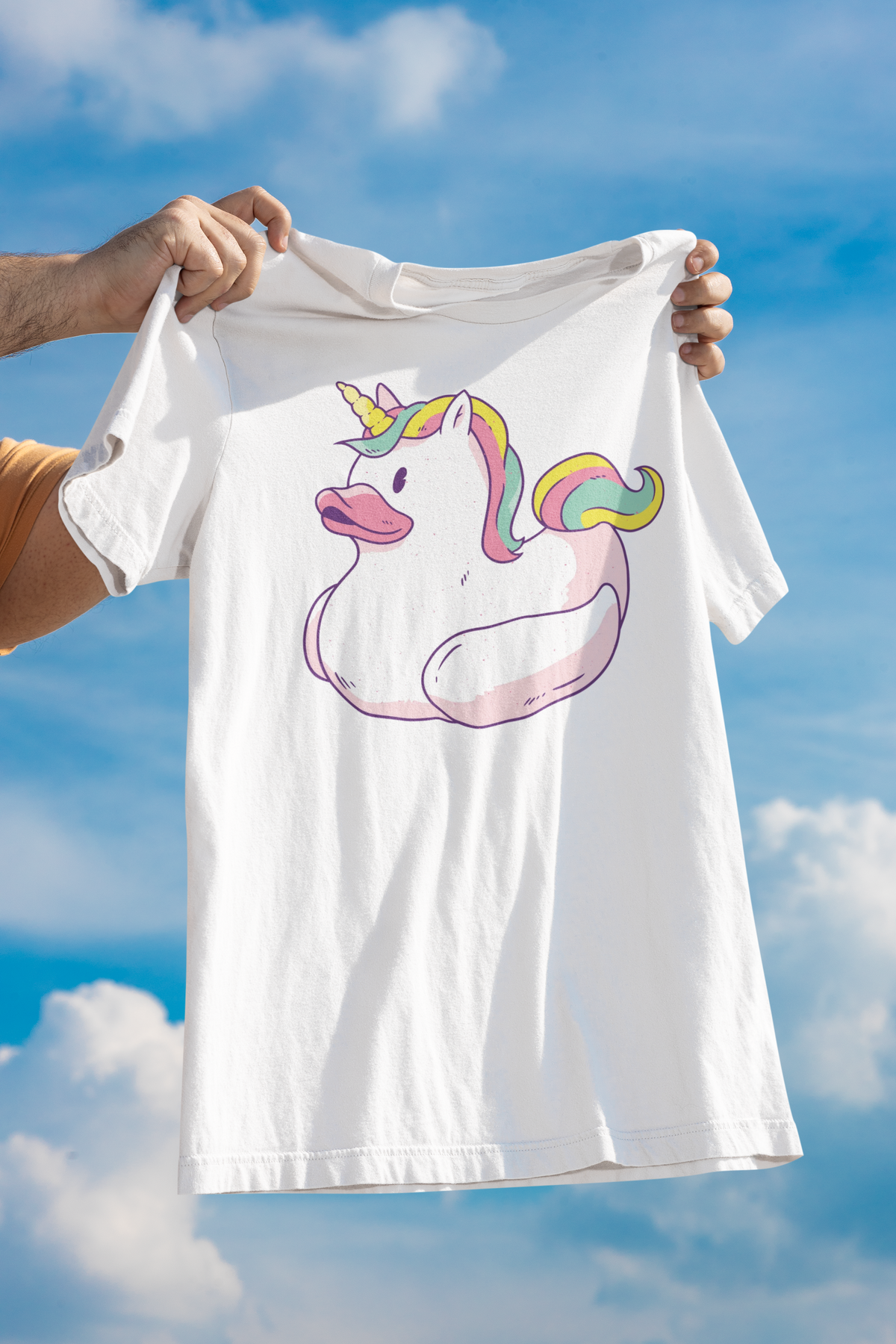 Unicorn duck t-shirt in white, held up outdoors against a cloudy sky backdrop, funny whimsical gift shirt