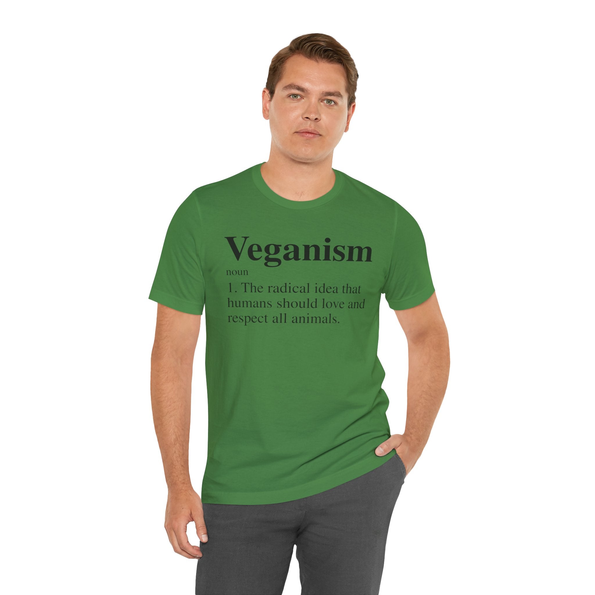Man in a green Veganism T-shirt with the word "veganism" and its definition printed on it, standing with one hand on his hip.