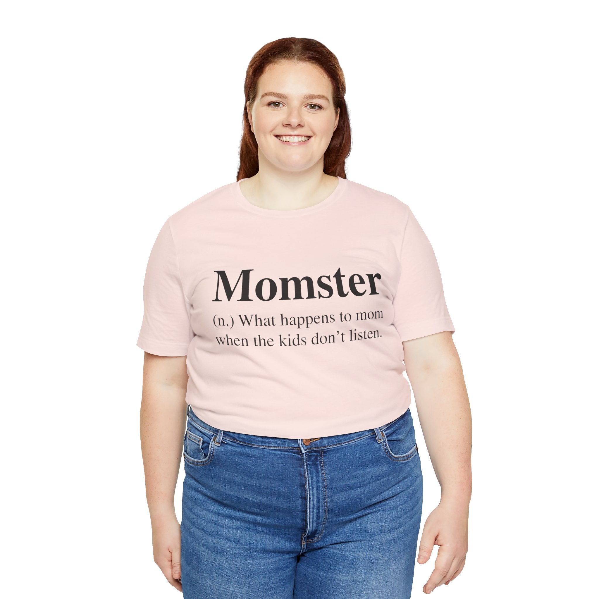 A woman in a Momster T-Shirt with the word "momster" and its humorous definition printed on it, paired with blue jeans, smiling at the camera.