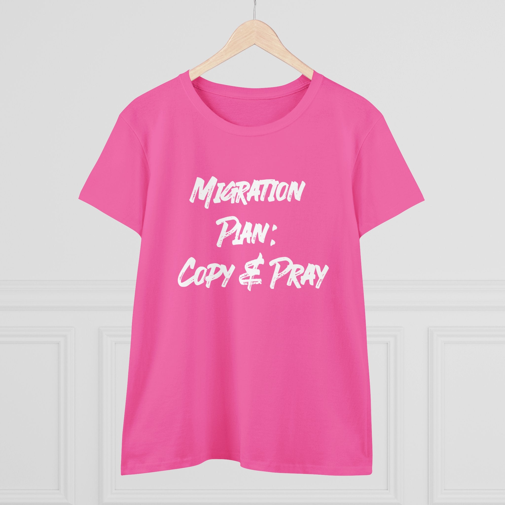 The "Migration Plan Copy and Pray" women's cotton tee, displayed on a hanger, features bold white lettering that adds a humorous and stylish flair to your wardrobe.