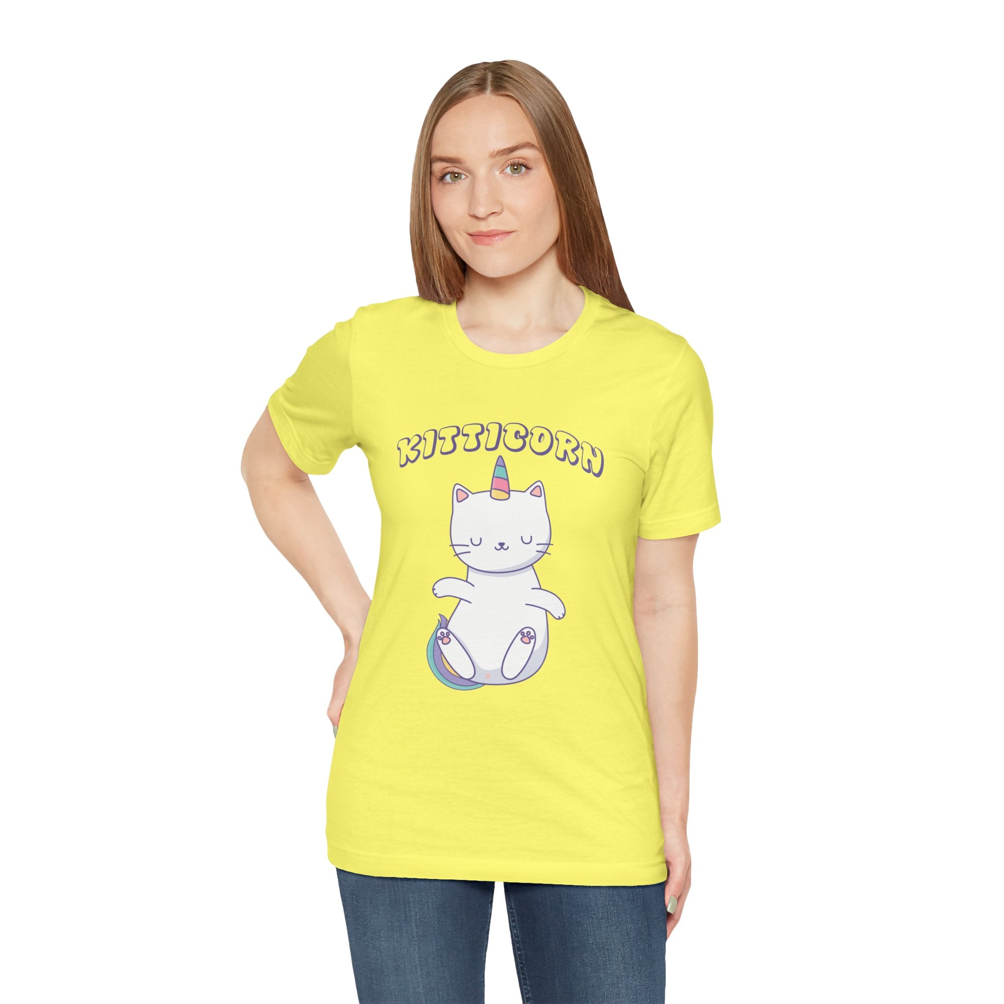 Woman in a yellow Kitticorn jersey tee with a cartoon unicorn cat design standing against a plain background.