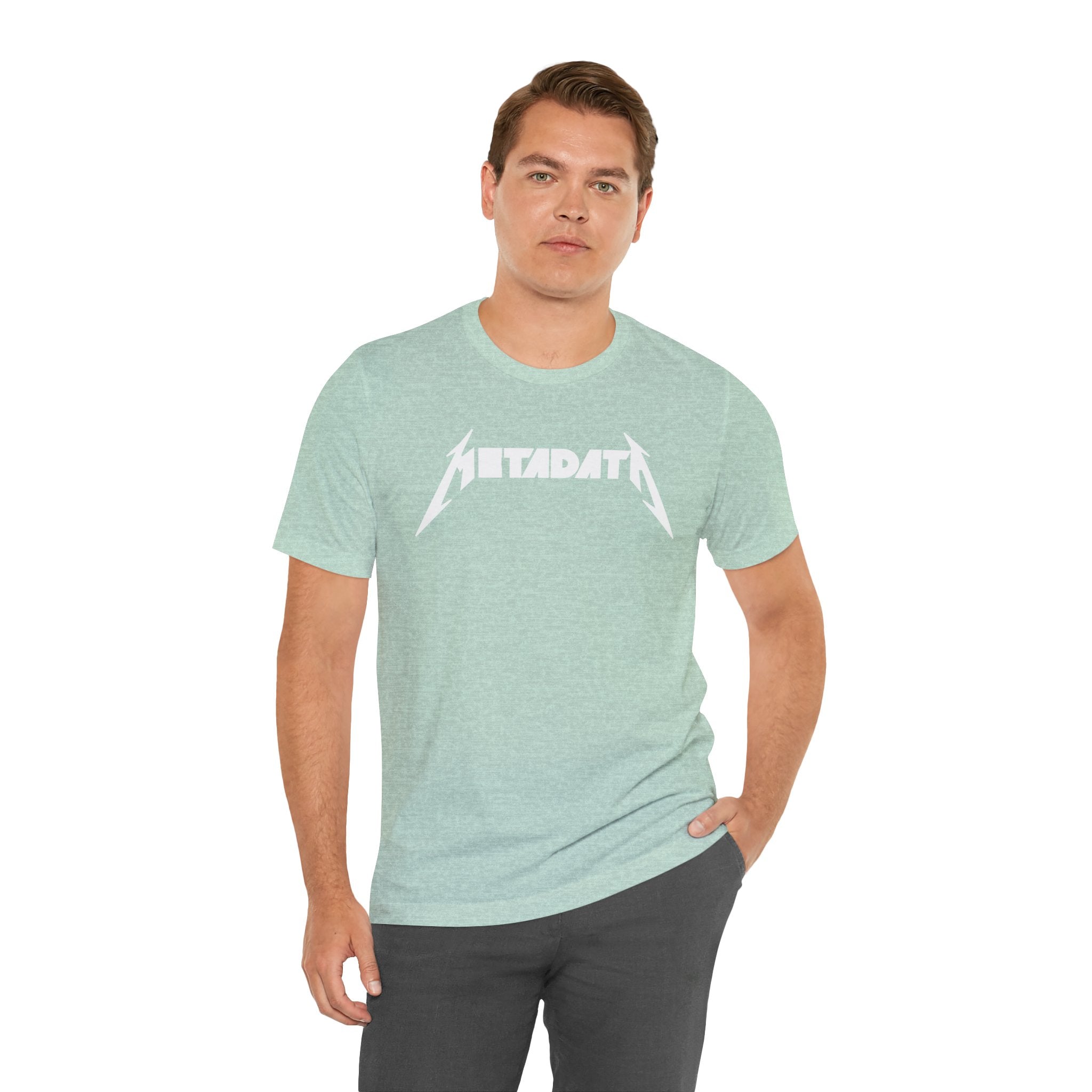 A person wearing the "Metadata" T-shirt in light green, featuring a white design and made from Airlume combed cotton for exceptional comfort, stands with one hand in their pocket.