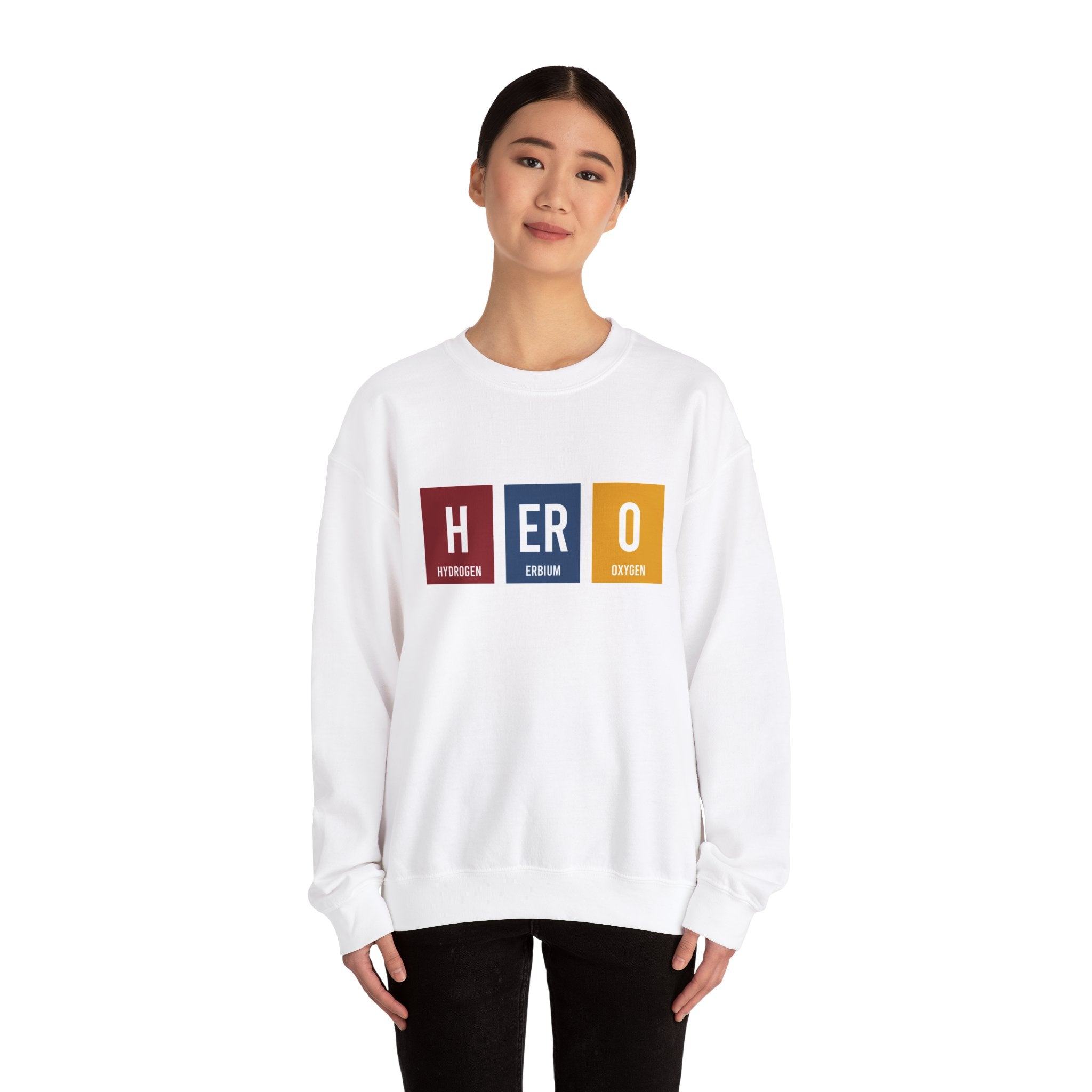Person wearing a HERO - Sweatshirt that perfectly balances comfort and style, with the word "HERO" printed in colorful blocks, each representing an element from the periodic table: Hydrogen, Erbium, and Oxygen. Ideal for making winters warmer with a touch of geeky flair.