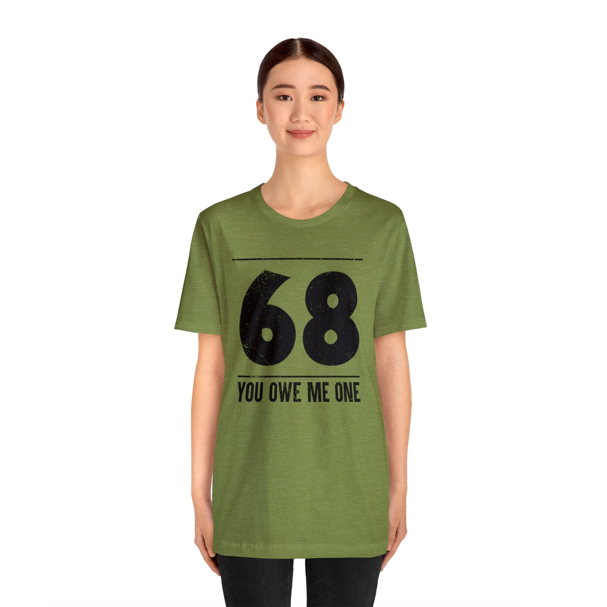 A woman in a geeky green shirt that says "68 You Owe Me One".