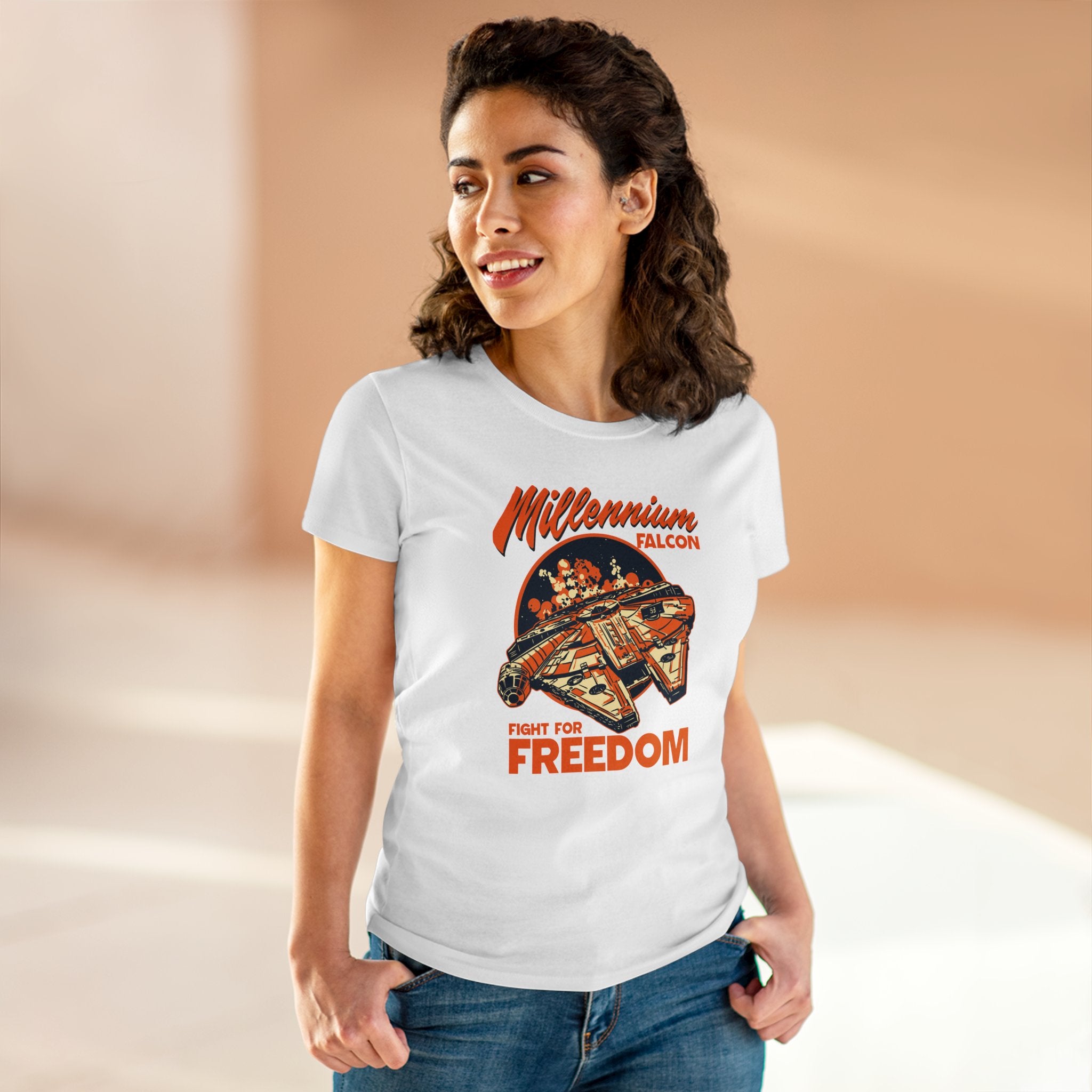 A woman is wearing a white Falcon - Women's Tee made from soft pre-shrunk cotton with a graphic of the Millennium Falcon and text that reads, "Fight for Freedom." She is posing, looking off to the side, with one hand in her pocket.