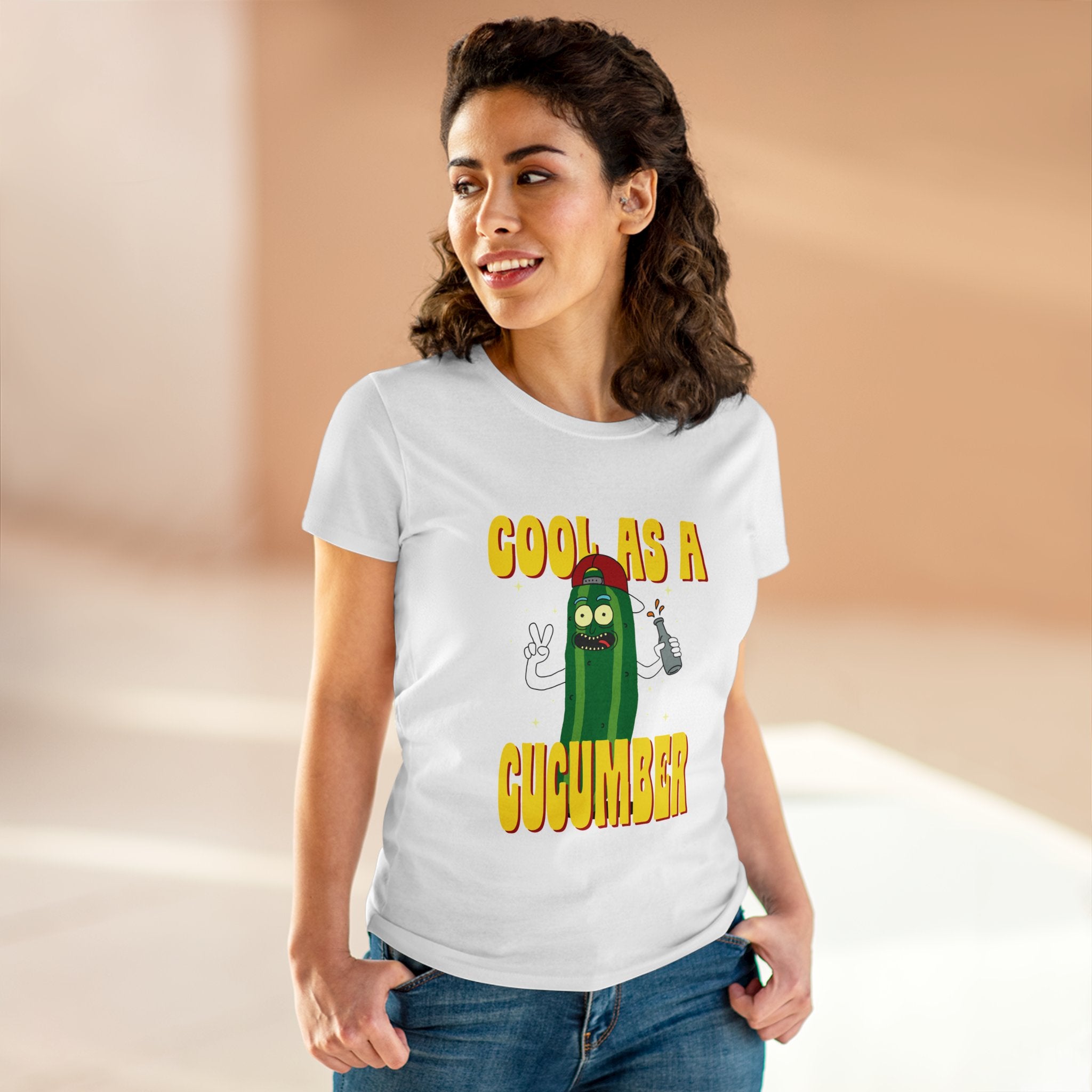 Woman standing and smiling, wearing a Cool as Cucumber - Women's Tee with a cartoon cucumber and the text "Cool as a Cucumber." The semi-fitted silhouette is crafted from pre-shrunk cotton for lasting shape and comfort.