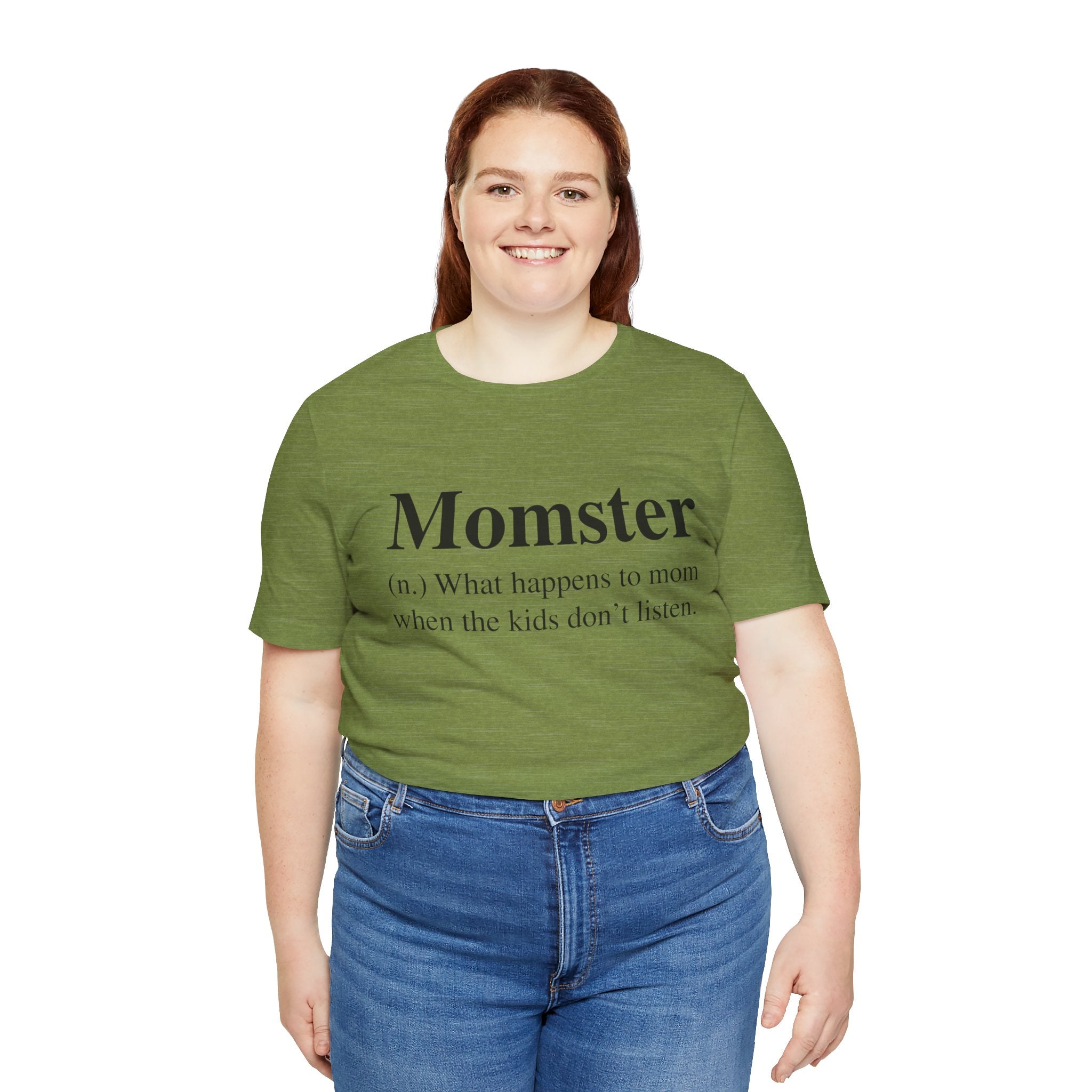 Woman smiling, wearing a green, soft cotton Momster T-shirt and blue jeans, standing against a white background.