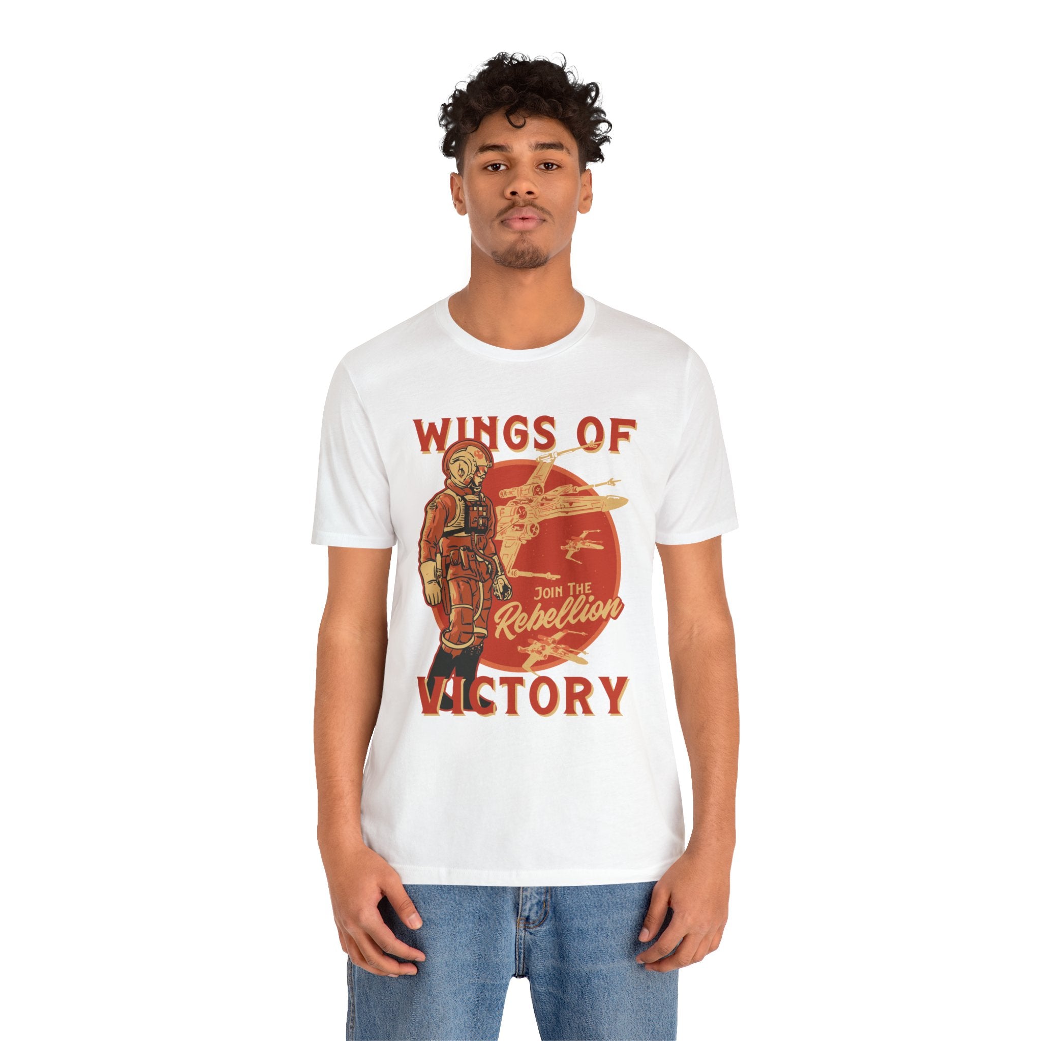 Man modeling a white unisex Wings of Victory T-Shirt with a quality print "wings of rebellion victory" graphic, paired with blue jeans, against a plain background.