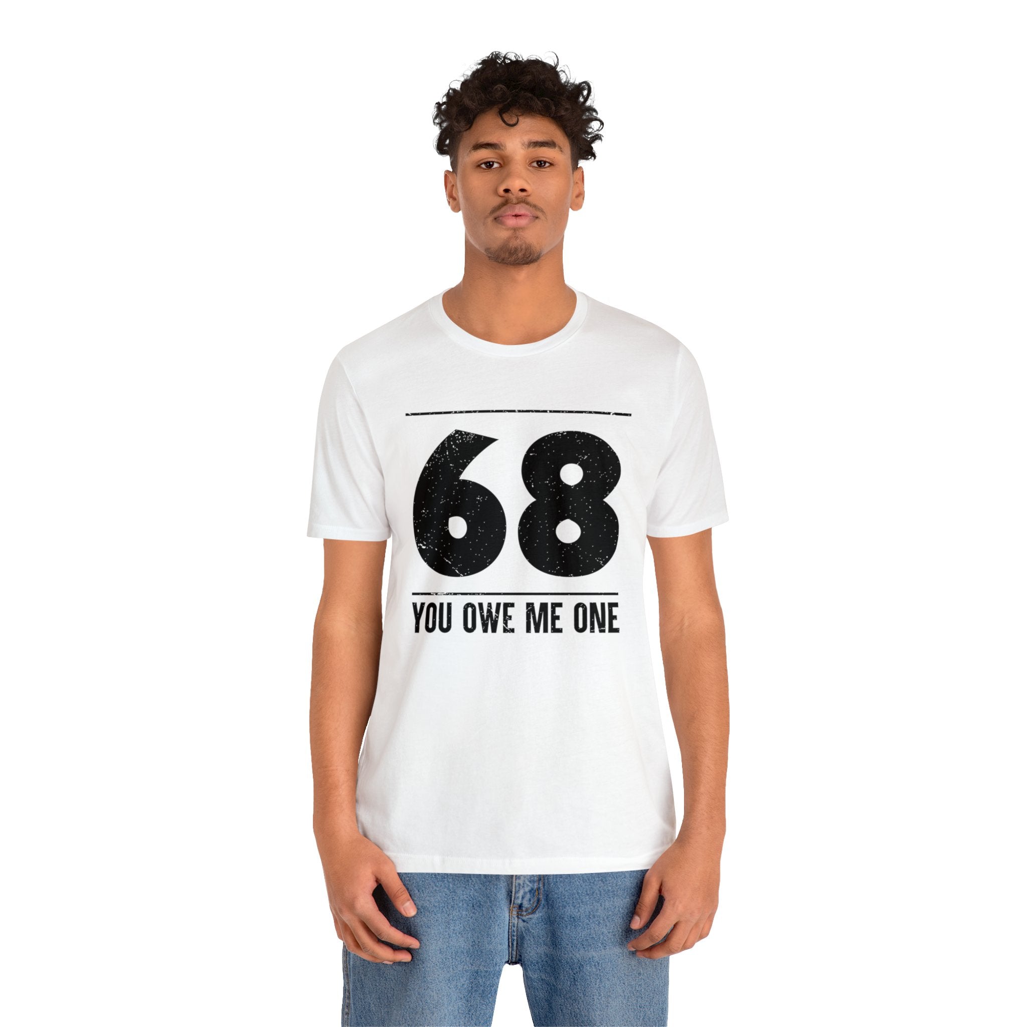 A man wearing a geeky white t-shirt that says 68 You Owe Me One.