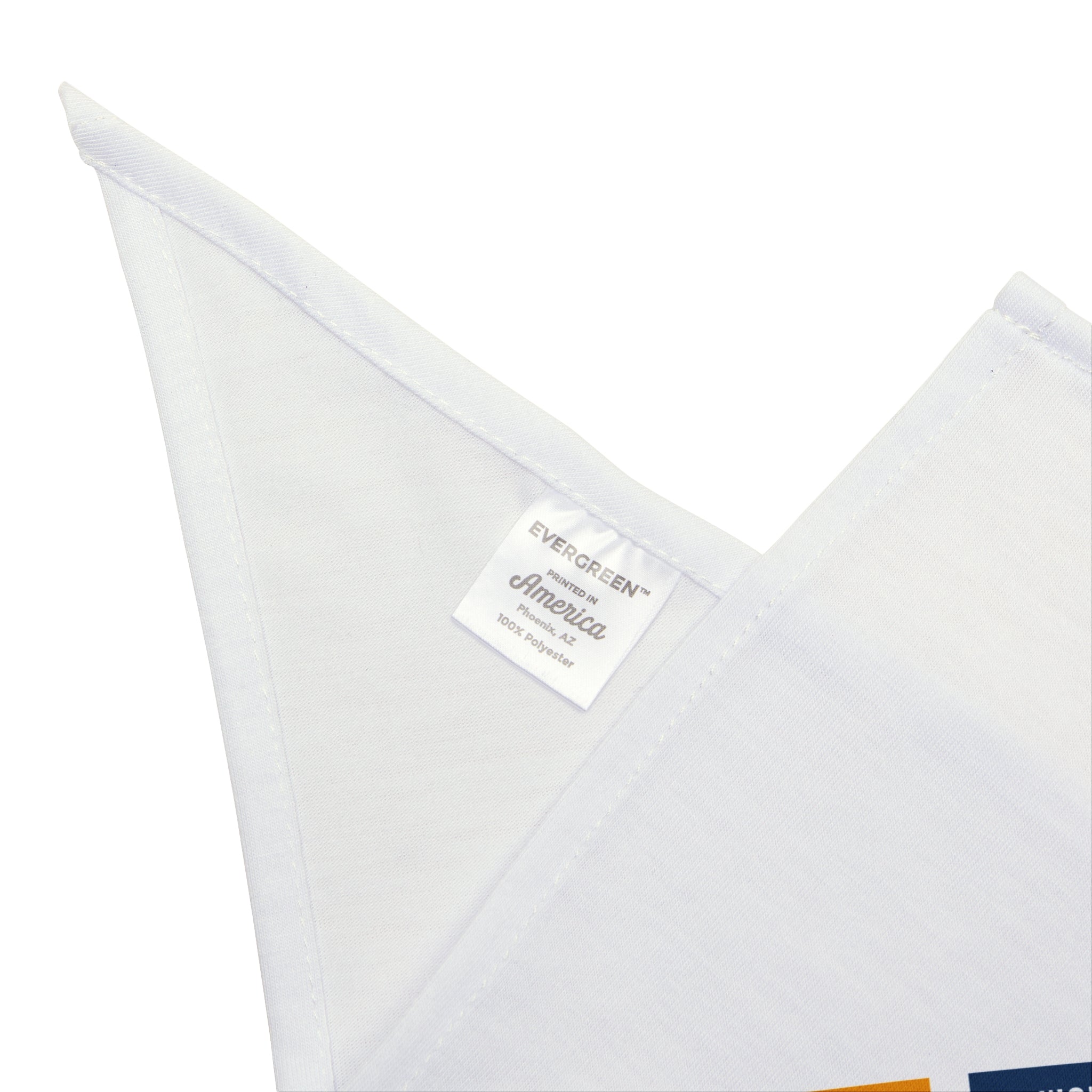 Close-up of a white triangular fabric piece with a label that reads "EVERGREEN America 100% Polyester," crafted from soft-spun polyester. This HERO - Pet Bandana is perfect for your furry friend, ensuring both durability and comfort for everyday adventures.
