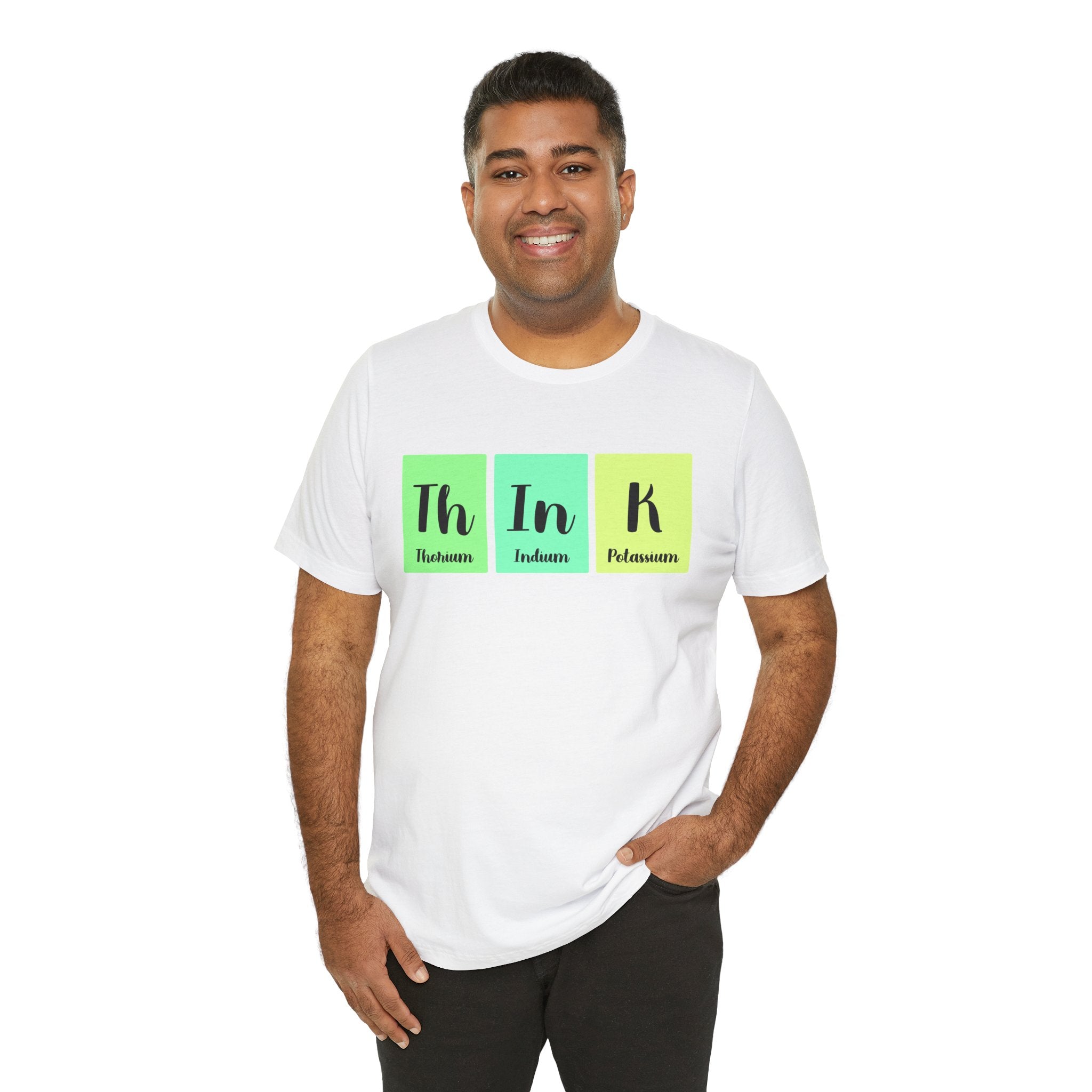 A man smiling at the camera, wearing a Th-In-k unisex jersey tee with "th in k" printed in green, blue, and yellow, representing elements from the periodic table.