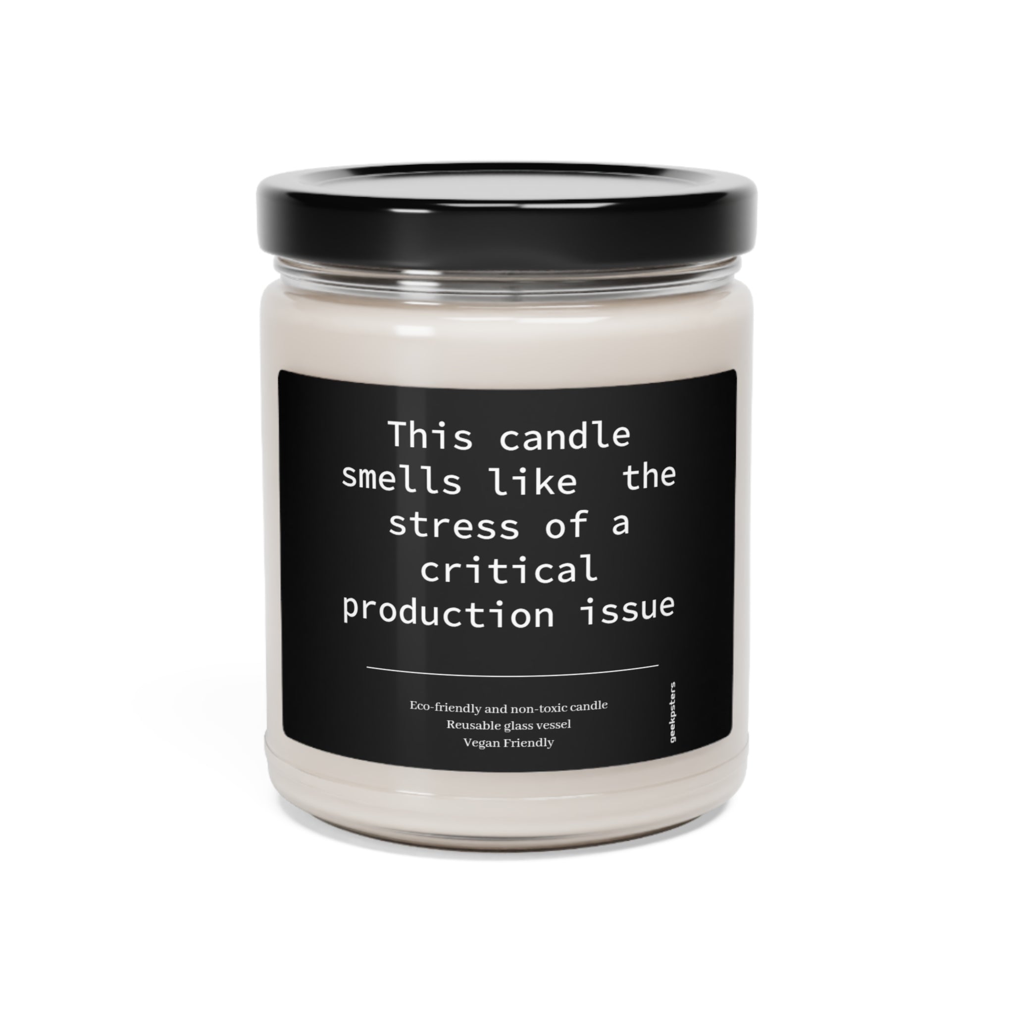 A scented soy candle in a clear glass jar with a black label reading "This Candle Smells Like the Stress of a Critical Production Issue," labeled as eco-friendly and vegan friendly.