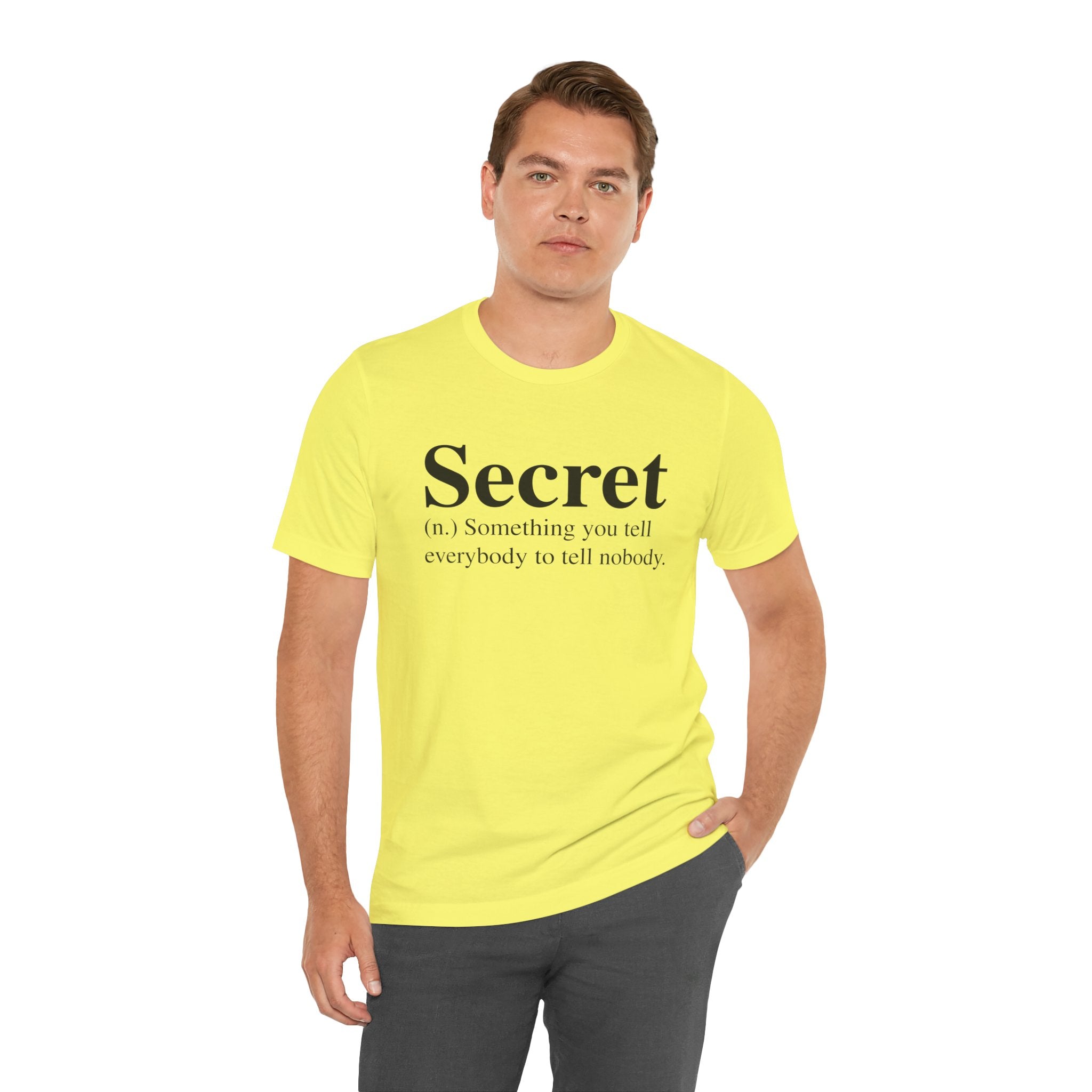 A man wearing a bright yellow Secret T - Shirt with the text "secret (n.) something you tell everybody to tell nobody.
