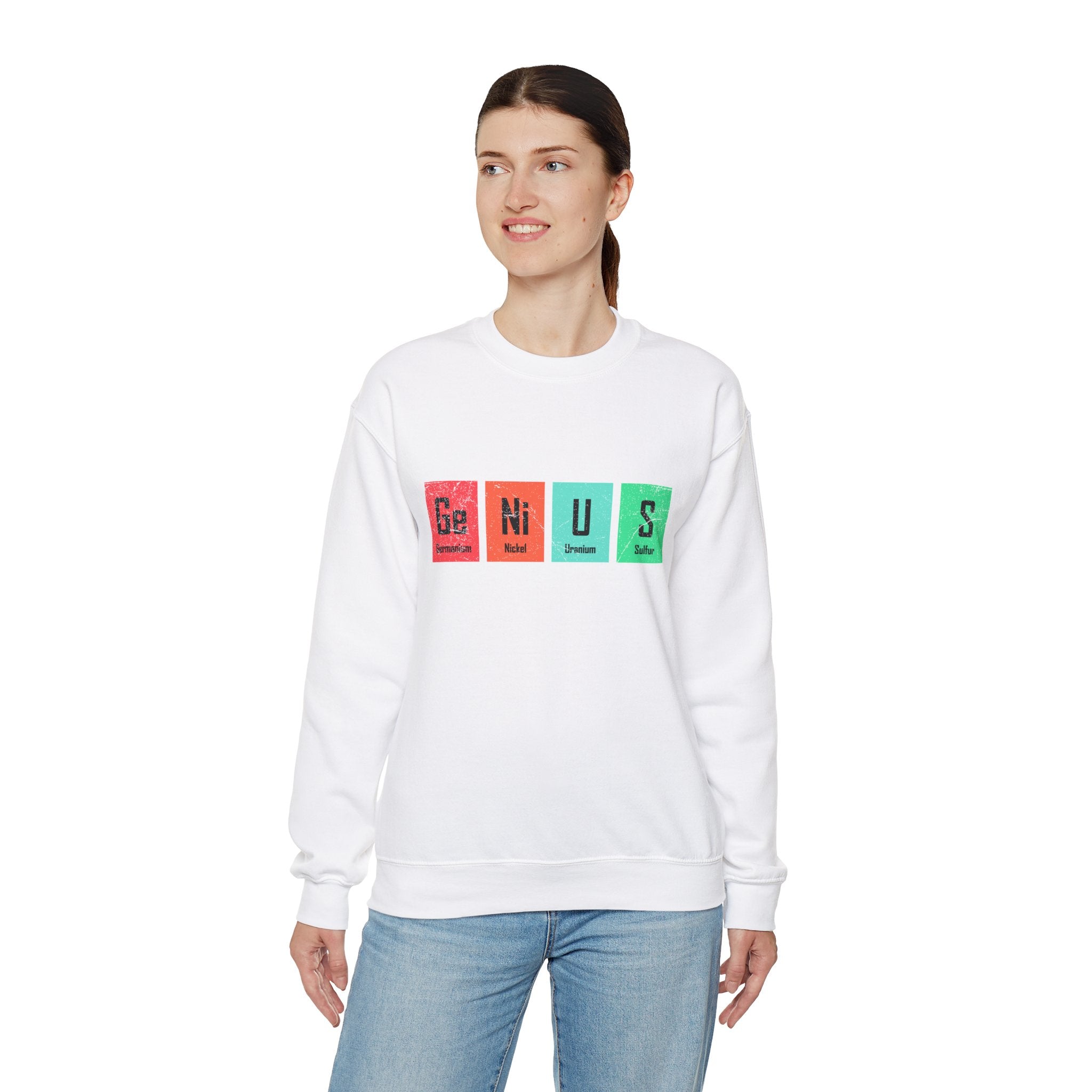A person wearing a white Ge-Ni-U-S - Sweatshirt that radiates warmth, with the word "GENIUS" spelled out in colorful blocks on the front. The person is looking to their left and has their hair pulled back.