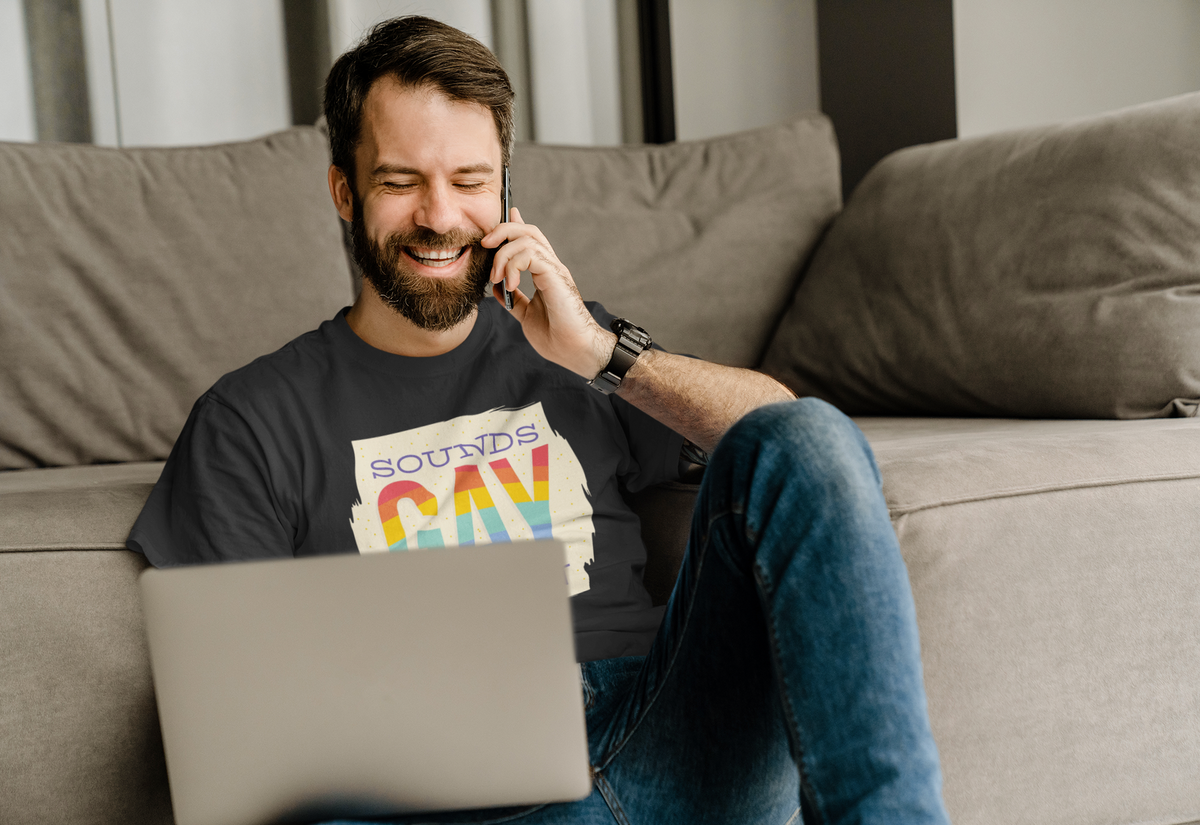 'Sounds Gay I'm In' T-shirt in black, man wearing it while relaxing on a couch, funny pride gift