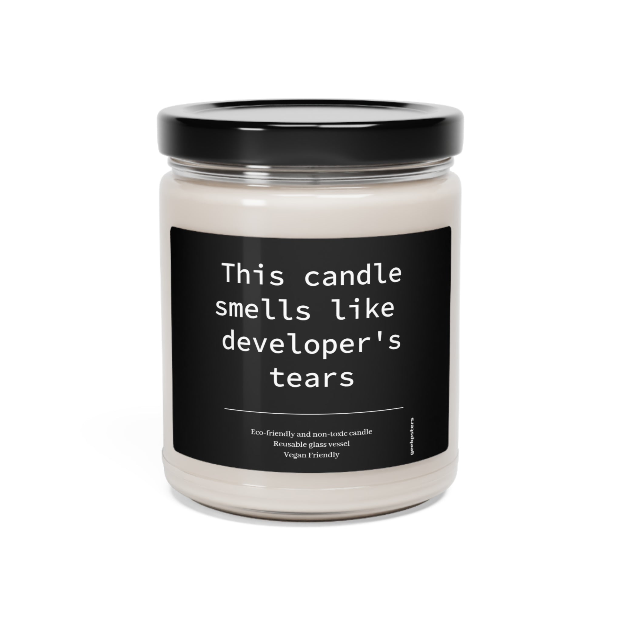 A This Candle Smells Like Developer's Tears- Scented Soy Candle, 9oz with the humorous label "this candle smells like developer's tears," indicating it's made from a soy wax blend, eco-friendly, and vegan-friendly.