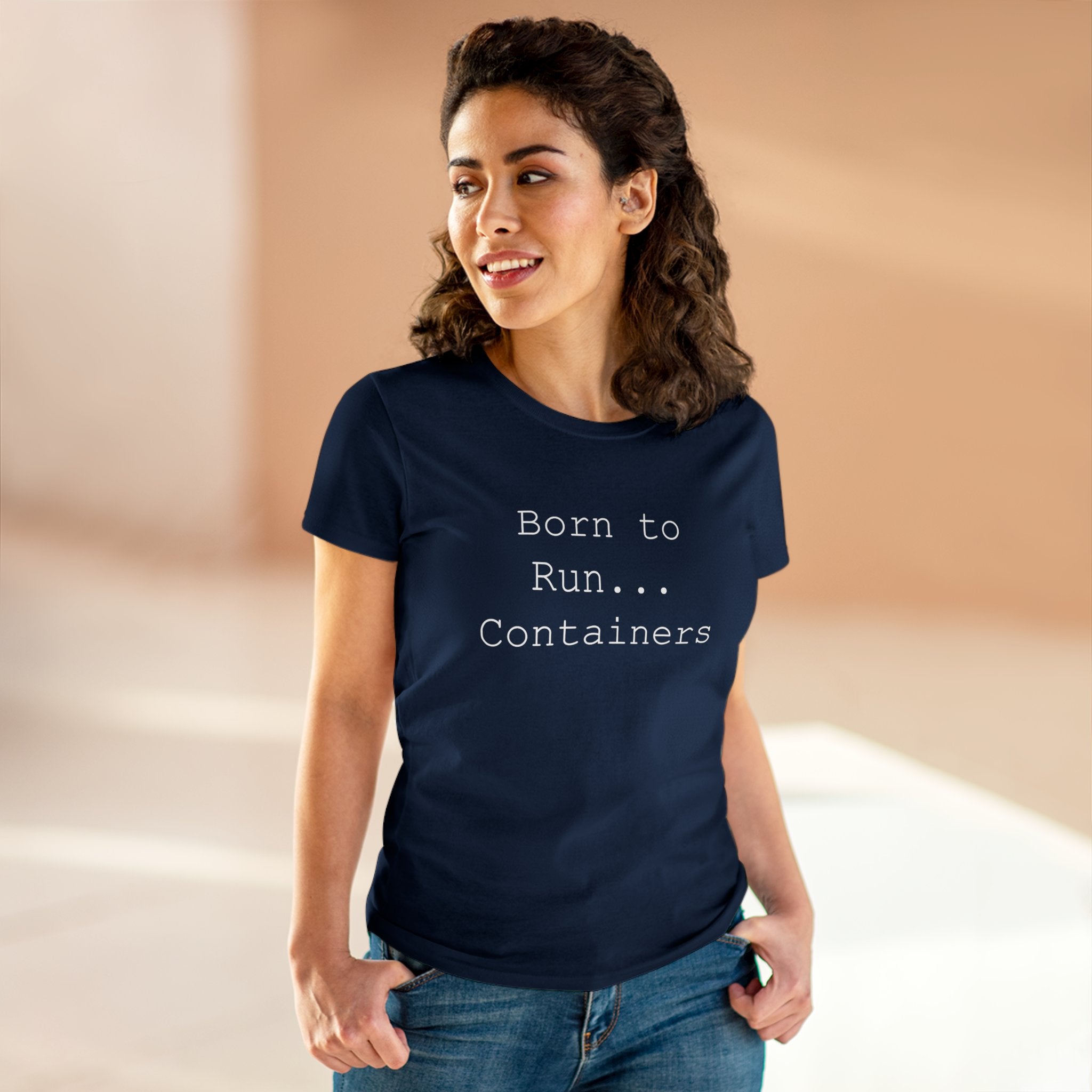 A person smiles slightly while indoors, wearing a wardrobe essential: the "Born to Run Containers" Women's Tee in navy.