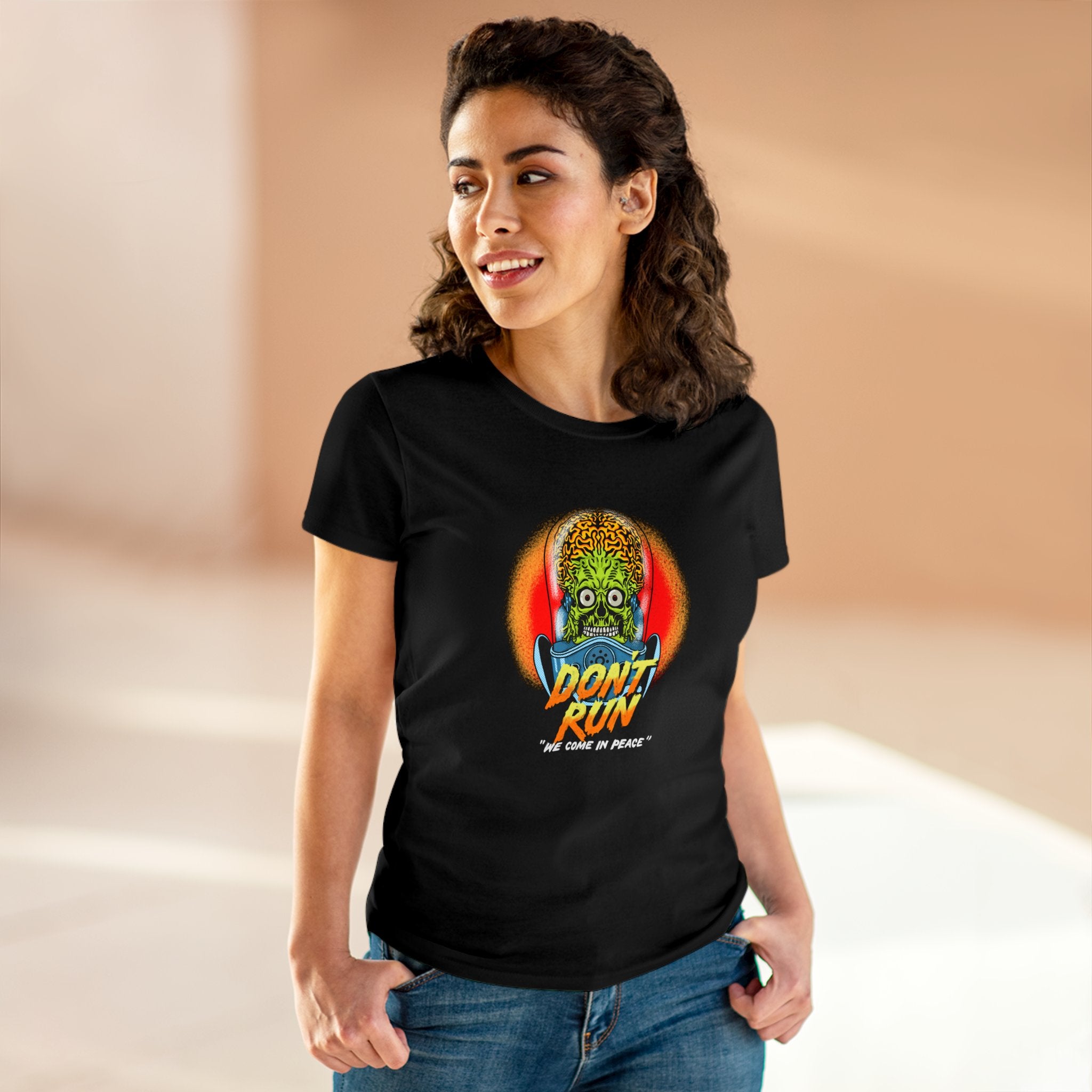 A woman wearing a black T-shirt with a colorful graphic and the text "Don't Run" stands in an indoor setting with a light brown background. The soft cotton fabric of the Don't Run - Women's Tee ensures a great fit.