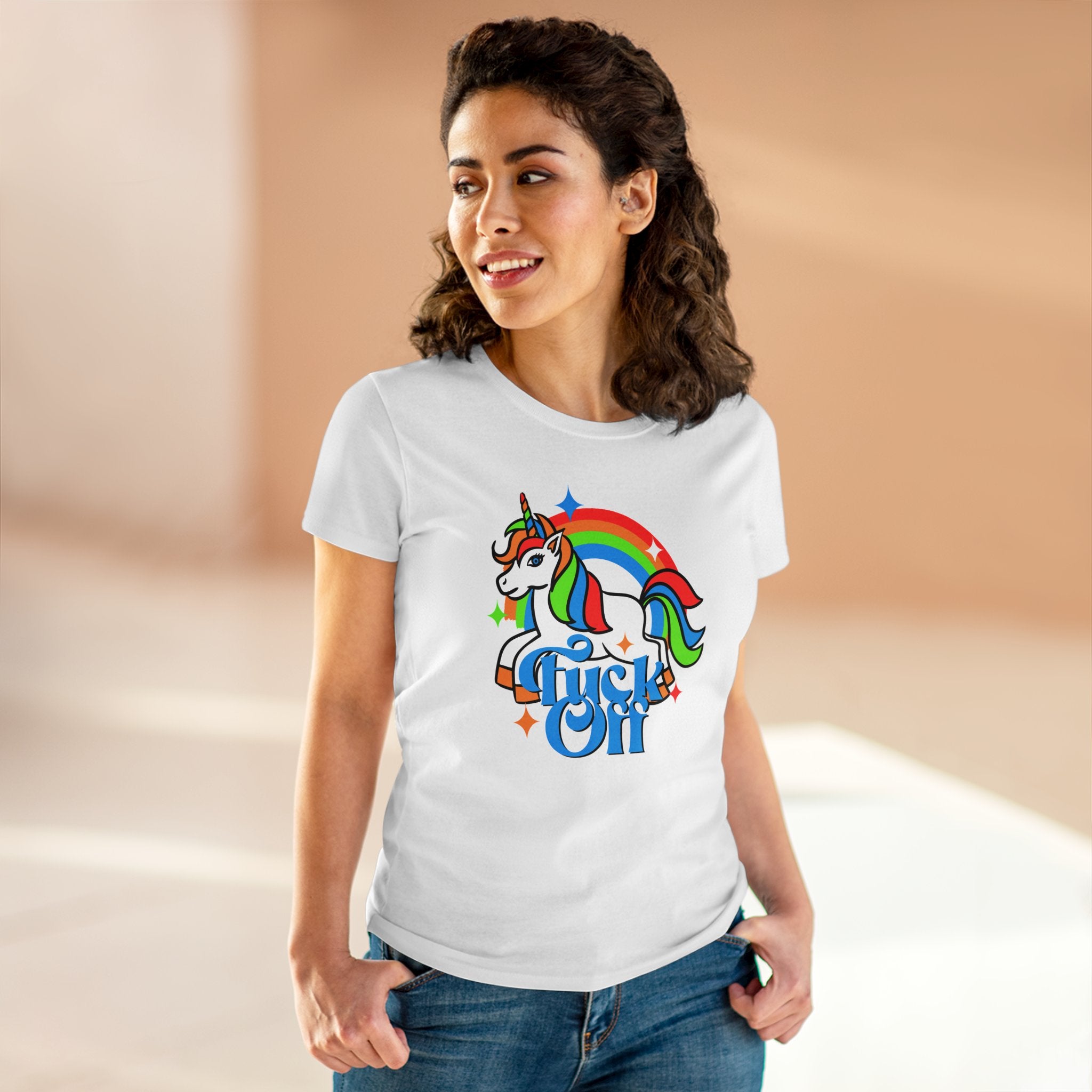 A woman stands indoors wearing an F Off - Women's Tee made of lightweight cotton, adorned with a bold design featuring a colorful unicorn and rainbow graphic that says "Magical AF.