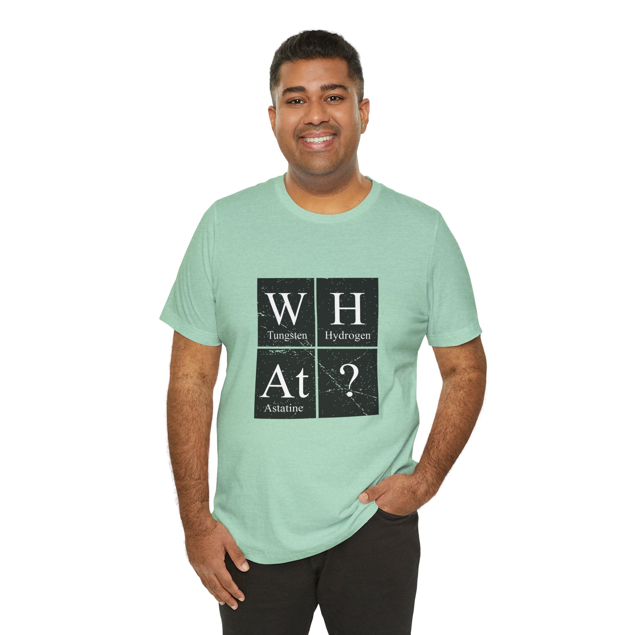 Man in a green unisex jersey tee with a W-H-At-? periodic table design, standing against a white background, smiling at the camera.