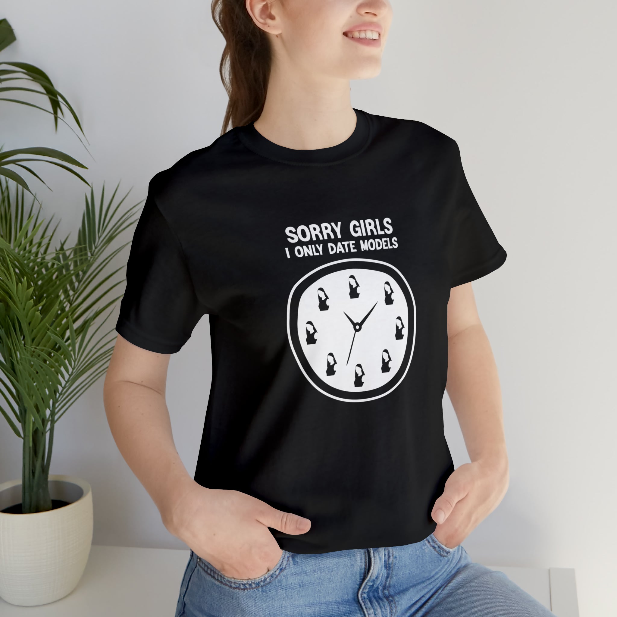 A stylish woman wearing a black "Sorry Girls I Only Date Models" t-shirt with a bold statement print that says sorry girls don't like clocks.