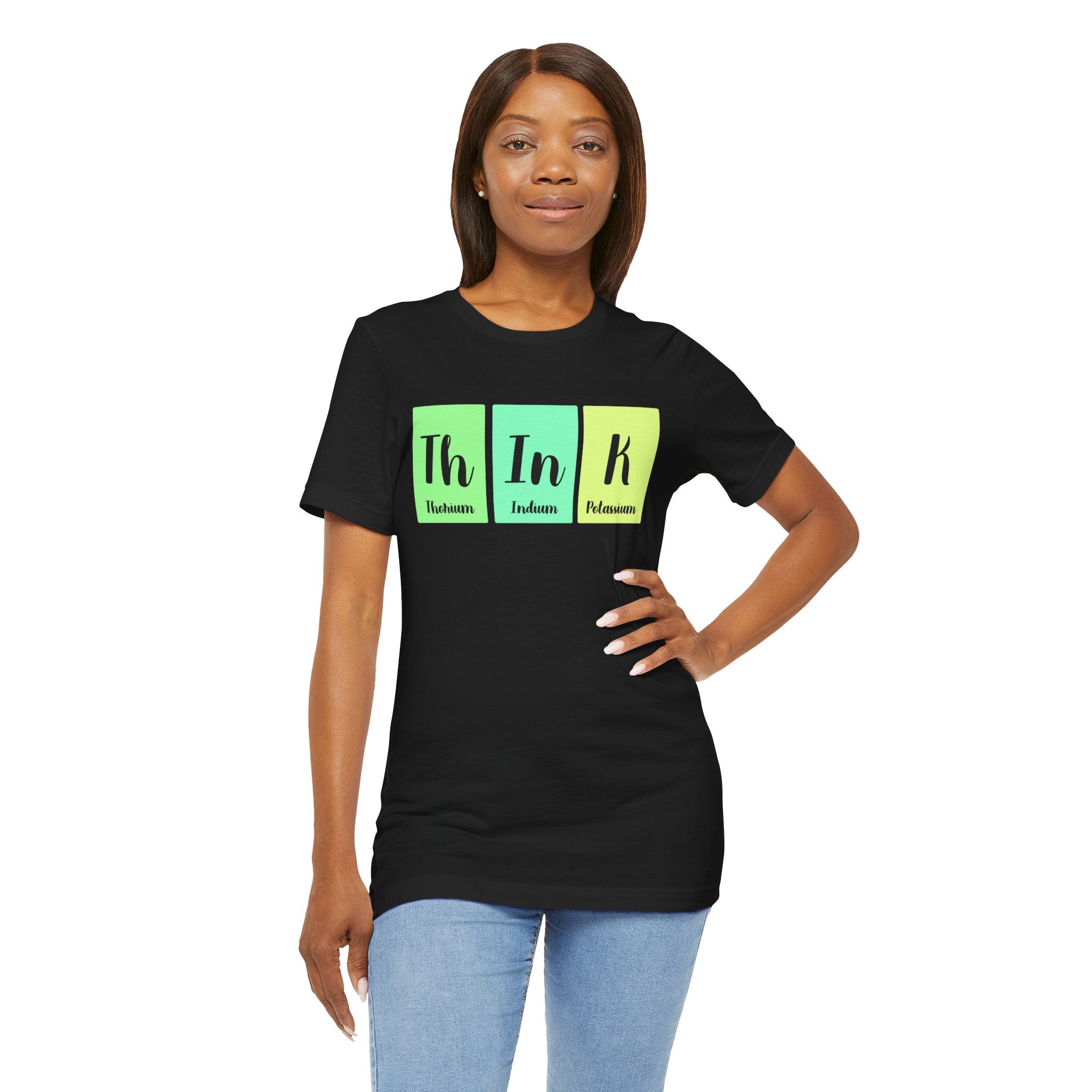 A woman standing, wearing a Th-In-k jersey tee in black with "th in k" in green and blue lettering representing thorium, indium, and potassium elements.