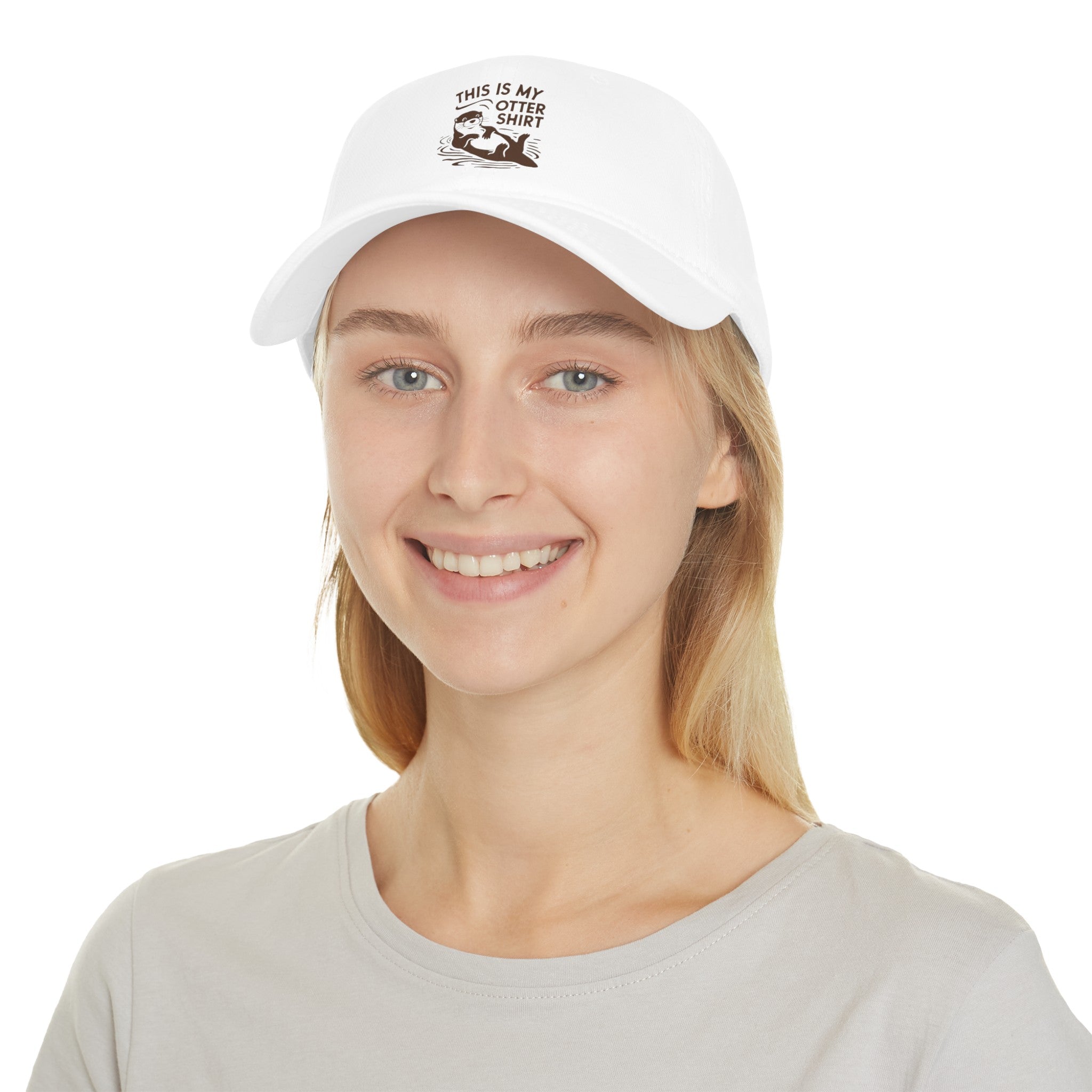 A person with long blonde hair smiles while wearing a white baseball cap, showcasing their unique style with an illustration and text that reads, "My Otter Shirt - Hat." They are dressed in a light grey t-shirt, exuding exceptional comfort.