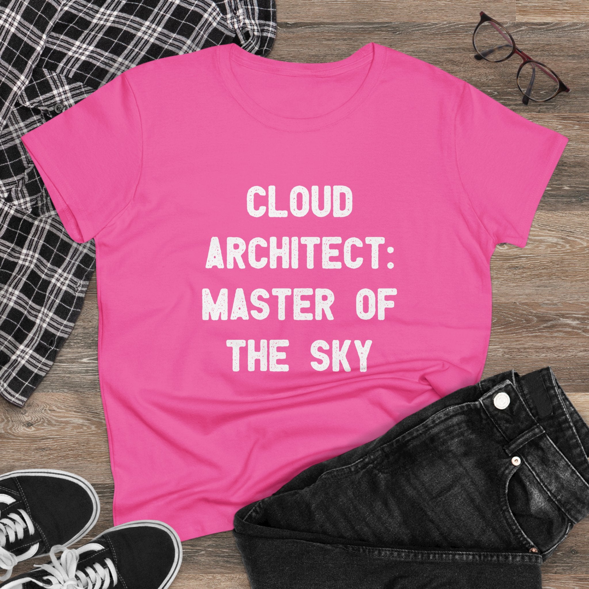 The Women's Tee, "Cloud Architect Master of the Sky," made from soft cotton, is showcased on a wooden floor. Its semi-fitted silhouette pairs seamlessly with black jeans, sneakers, a plaid shirt, and glasses for an effortlessly chic look.