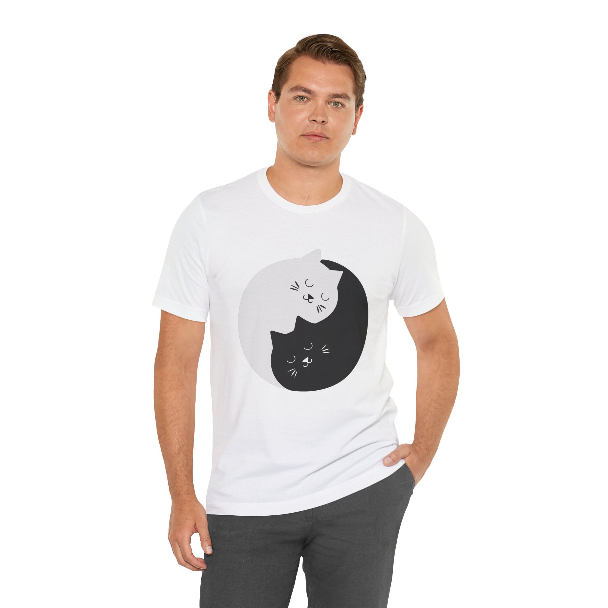 Man in a white YING- ANG KITTIES T-Shirt with a black cat graphic, standing against a plain background.