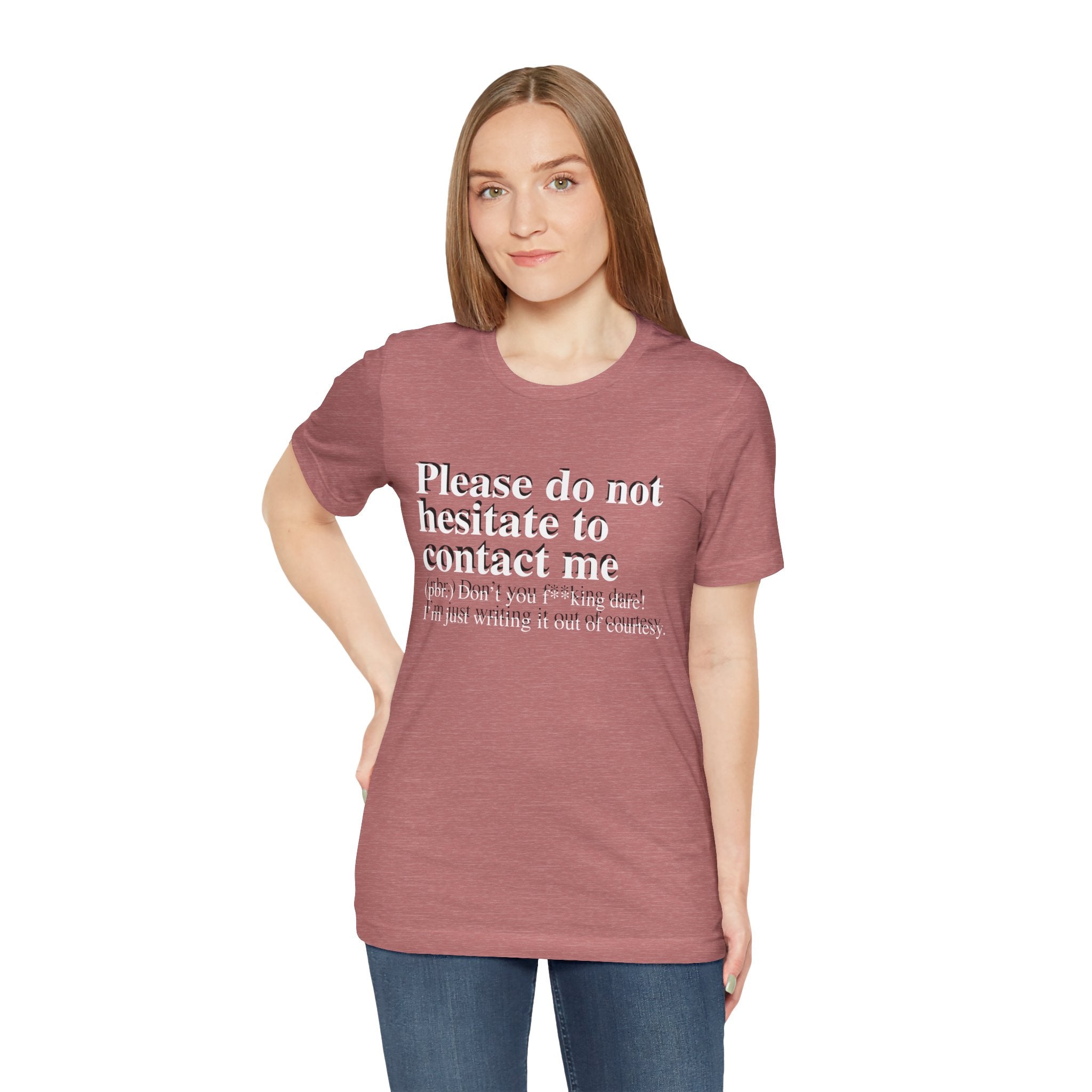 Young woman in a maroon, soft cotton Please Do Not Hesitate to Contact Me T-shirt smiles slightly at the camera.