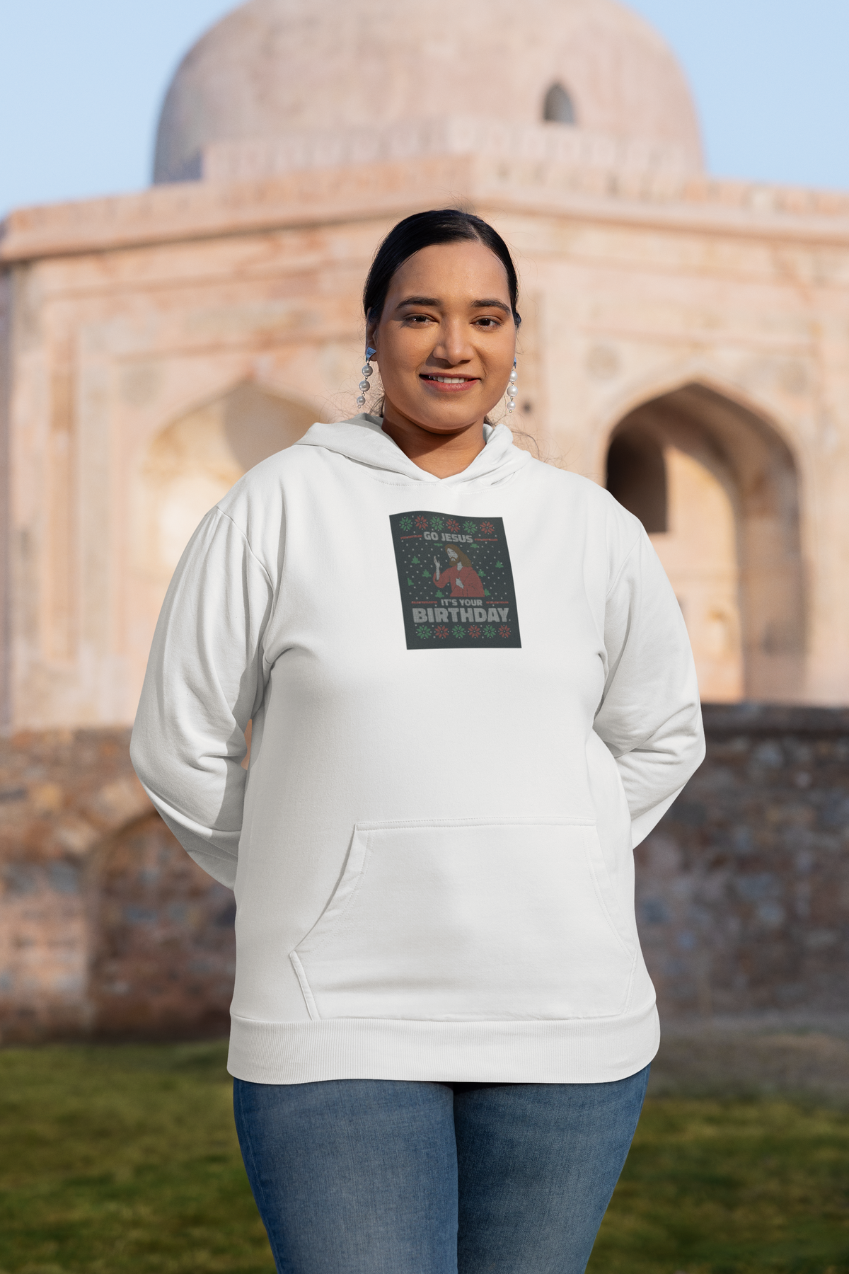 'Go Jesus It's Your Birthday Ugly Sweater Hoodie' in white, woman at a historic monument, Hoodie mockup, Geekpsters