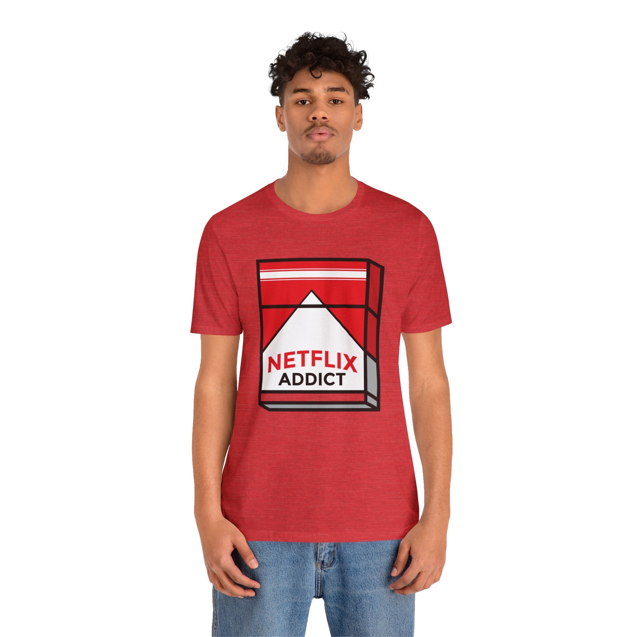 Young man in a red unisex Netflix Addict tee, standing against a white background.