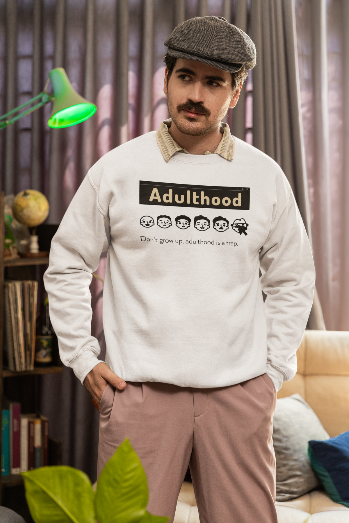 'Adulthood is a Trap' sweatshirt in sand, mustached man wearing it indoors, funny sarcastic gift