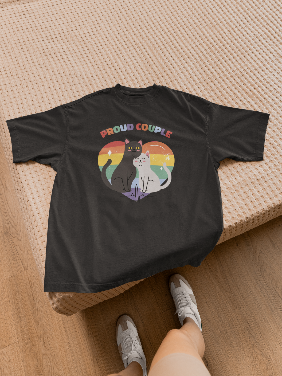 'Proud Couple of Cats' t-shirt in black, flat lay on a wooden bench with sneakers