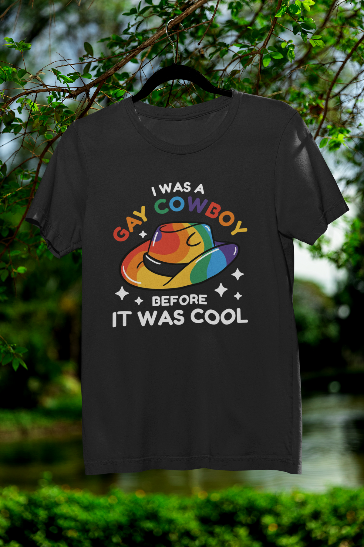 'I Was a Gay Cowboy Before It Was Cool' T-shirt in black, hanging outdoors, funny pride gift shirt