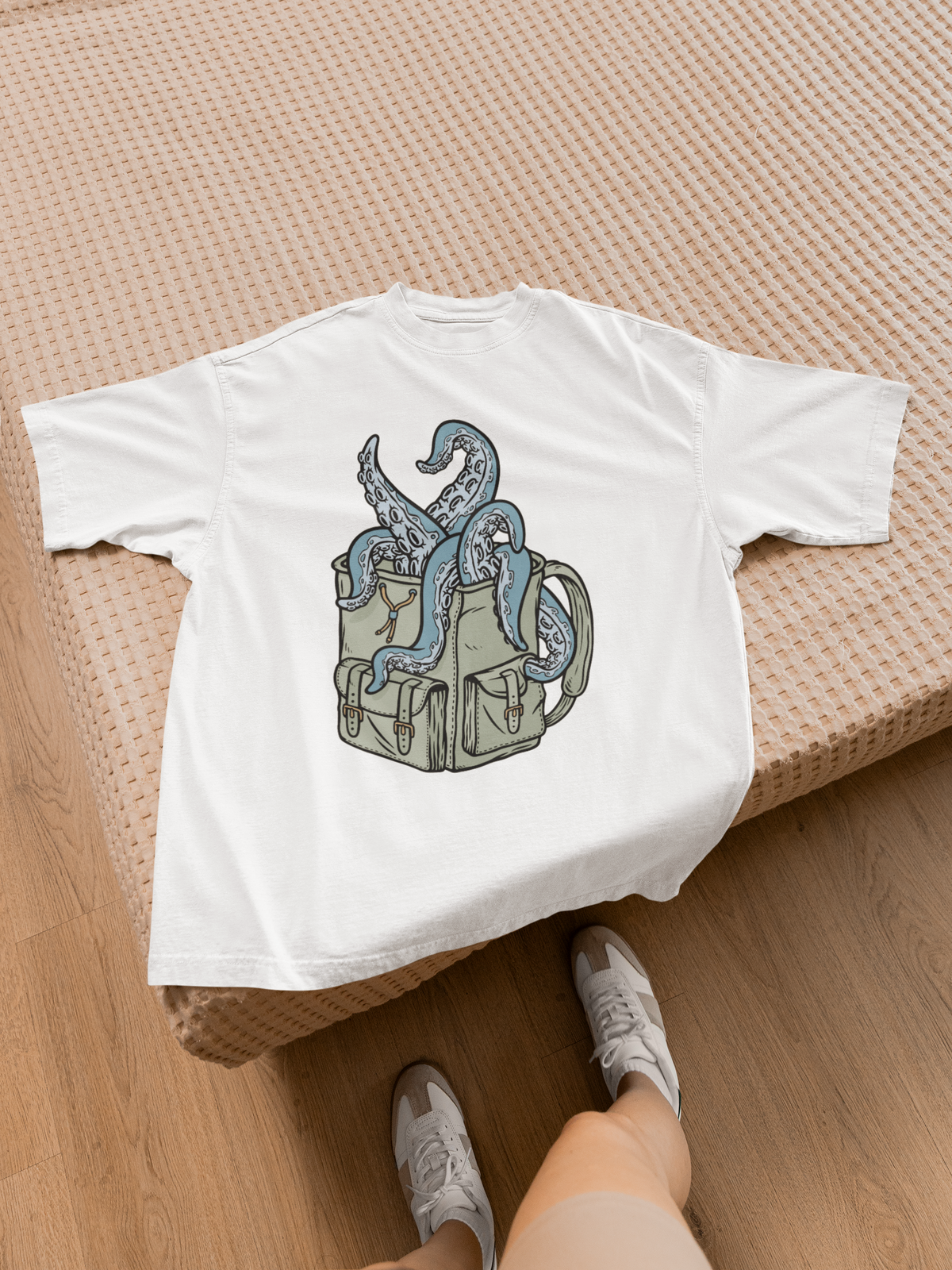 'Octopus Comes Out of the Bag' t-shirt in white, laid flat on a bed, funny gift for backpackers
