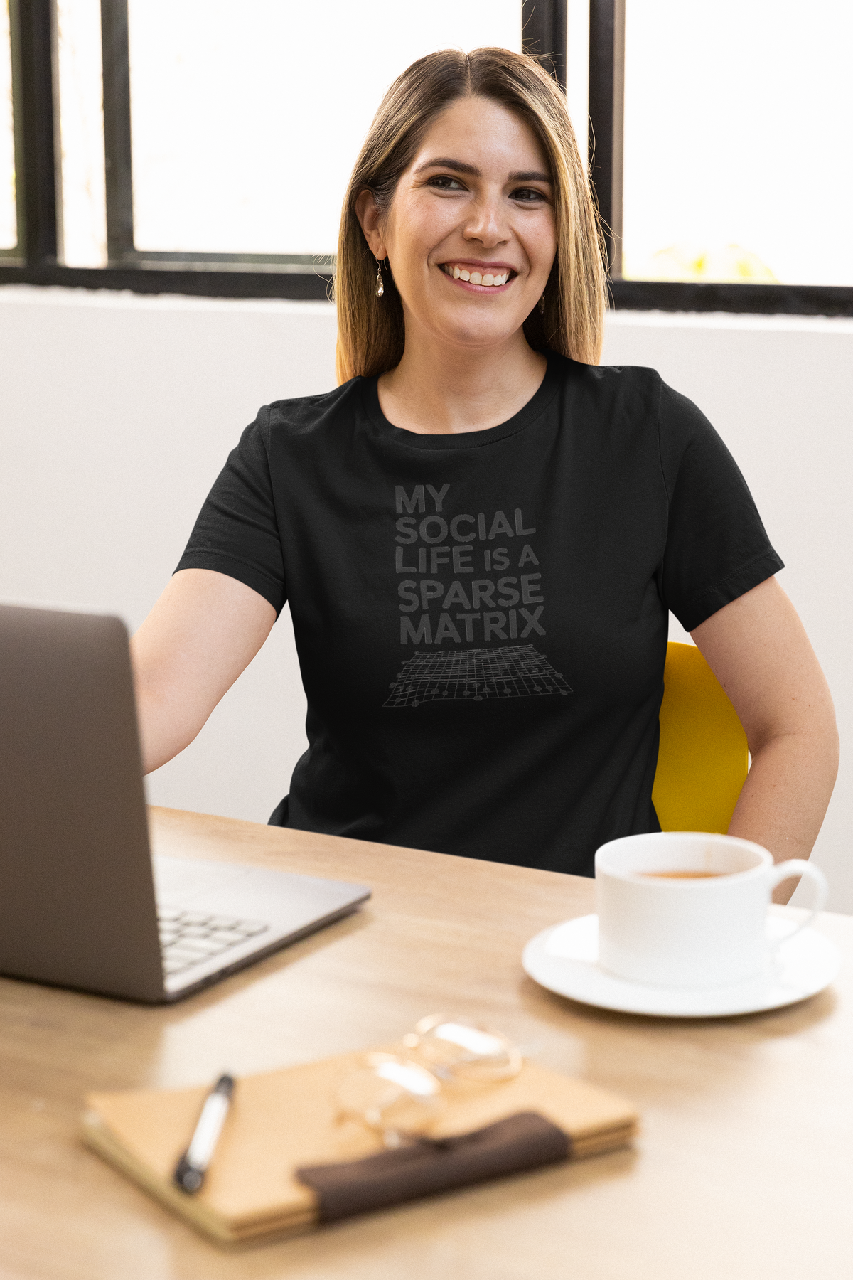 'My Social Life Is a Sparse Matrix' t-shirt in black, woman wearing it at an office desk, T-Shirt mockup, Geekpsters
