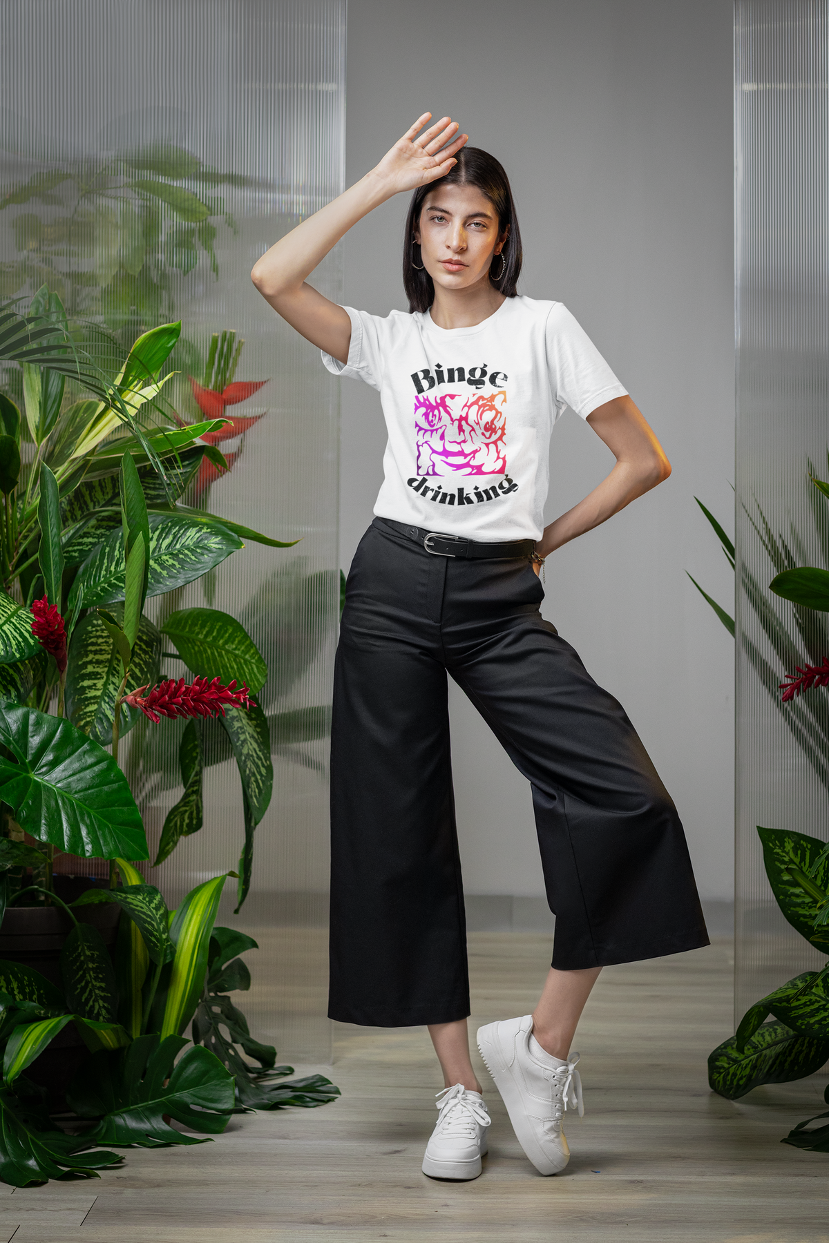 "Binge Drinking" graphic t-shirt in white, woman modeling it among plants, funny party gift shirt