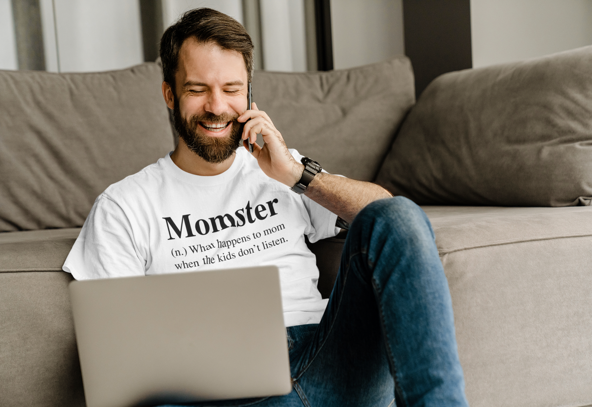 'Momster' definition T-shirt in white, man wearing it on the phone at home, funny mom humor gift tee