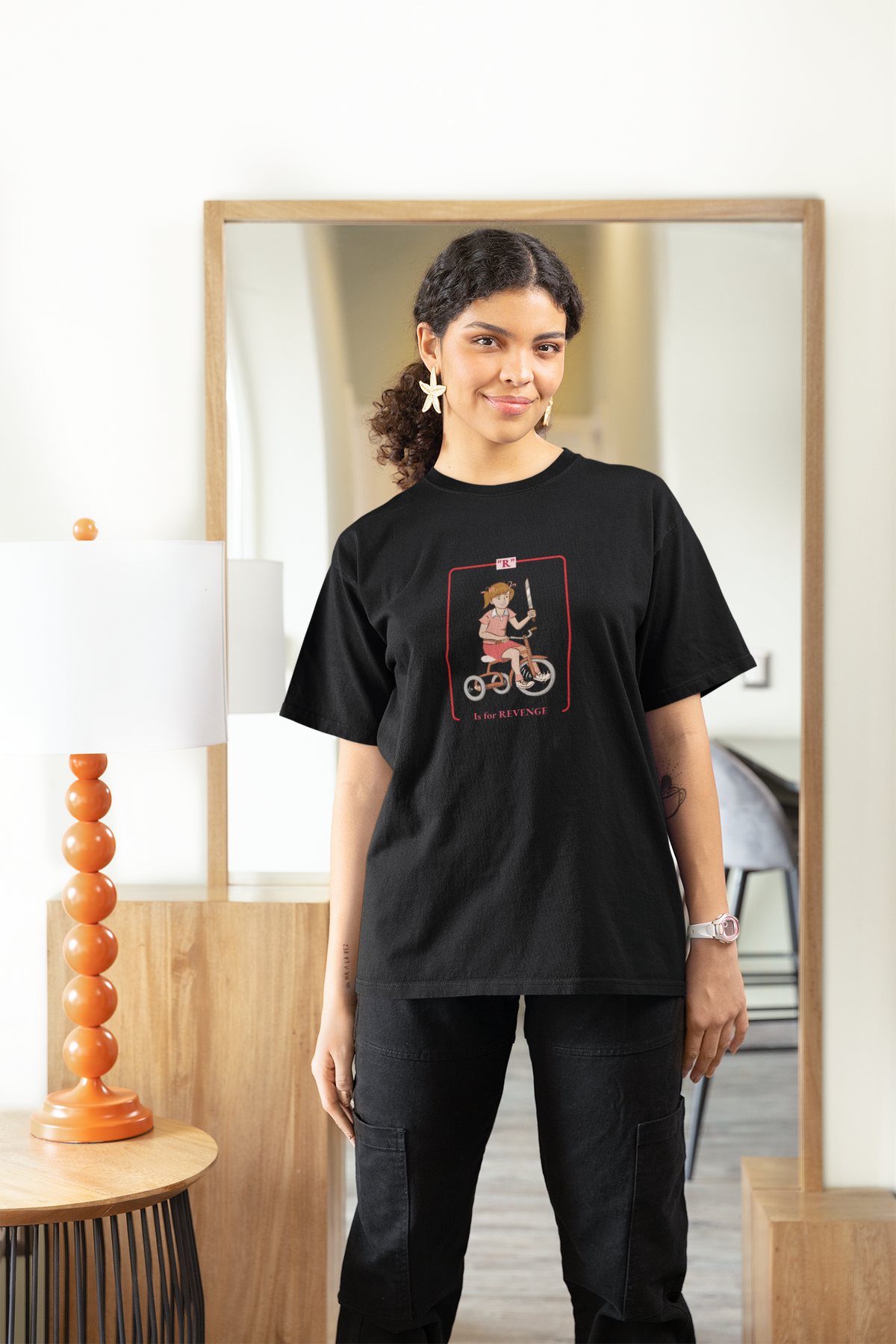 'R is for Revenge' tricycle girl graphic women's tee in black, woman wearing it at home, funny gift for her