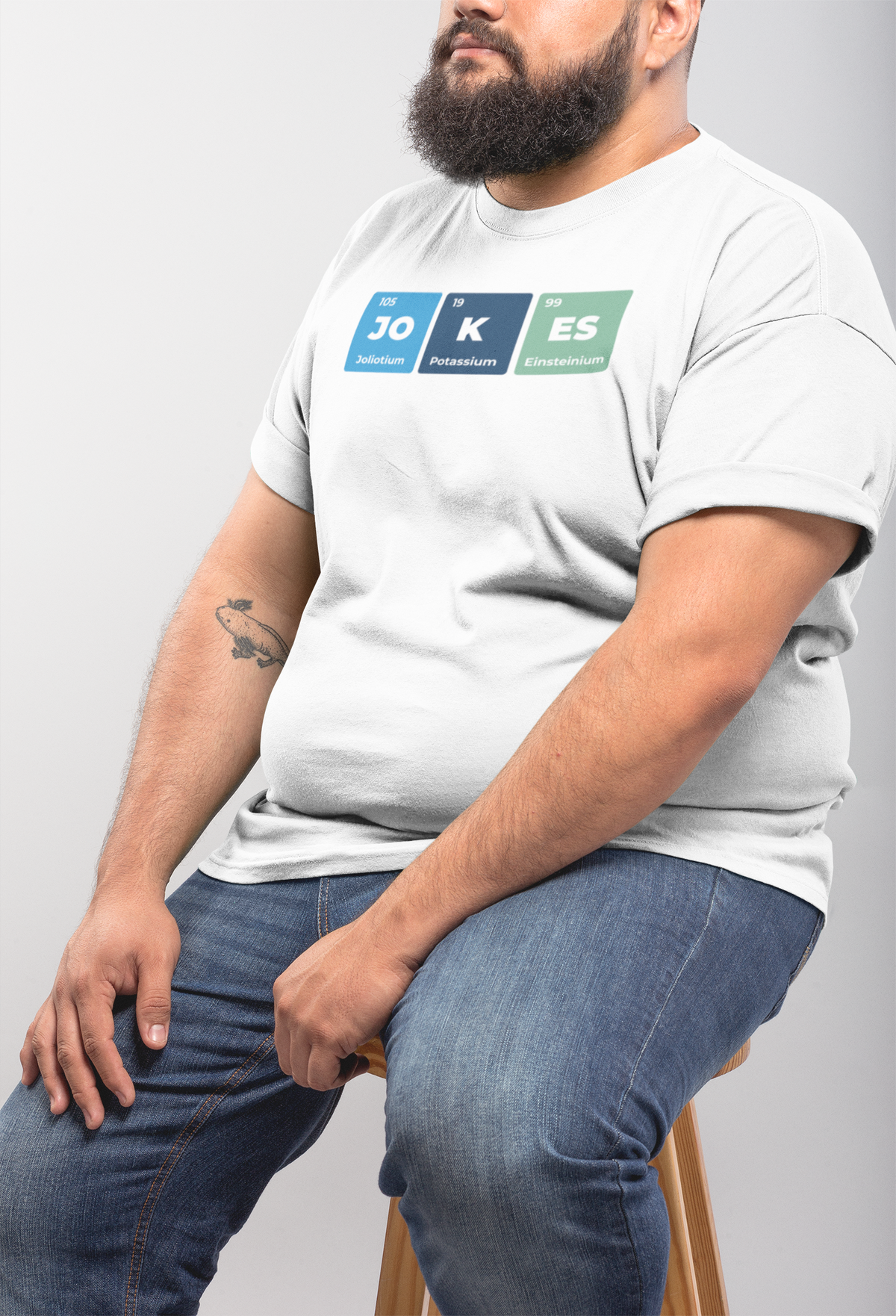 'Jokes' periodic table t-shirt in white, bearded man sitting wearing it