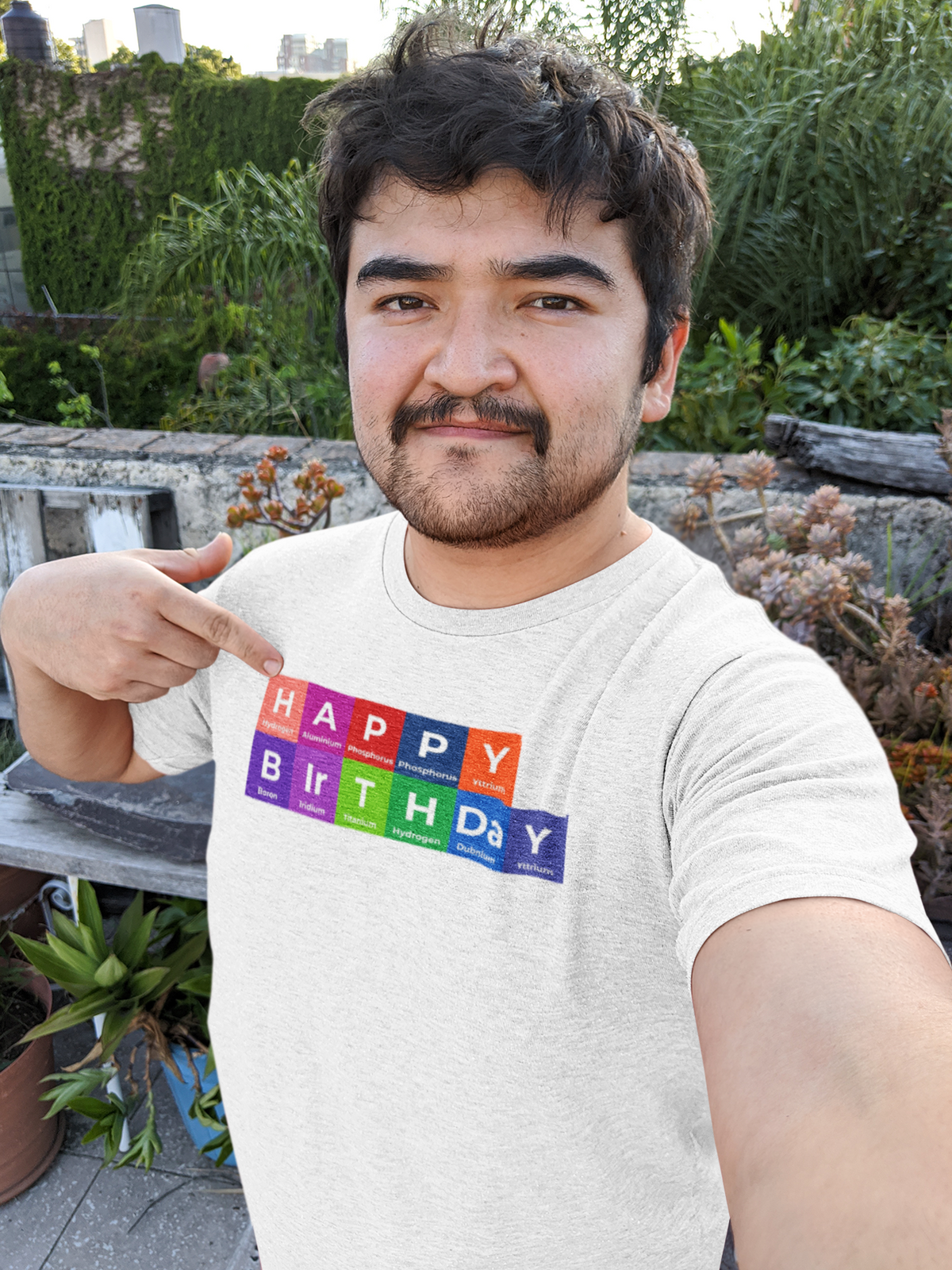 'Happy Birthday' periodic table t-shirt in heather grey, man pointing at the print, funny selfie style tee
